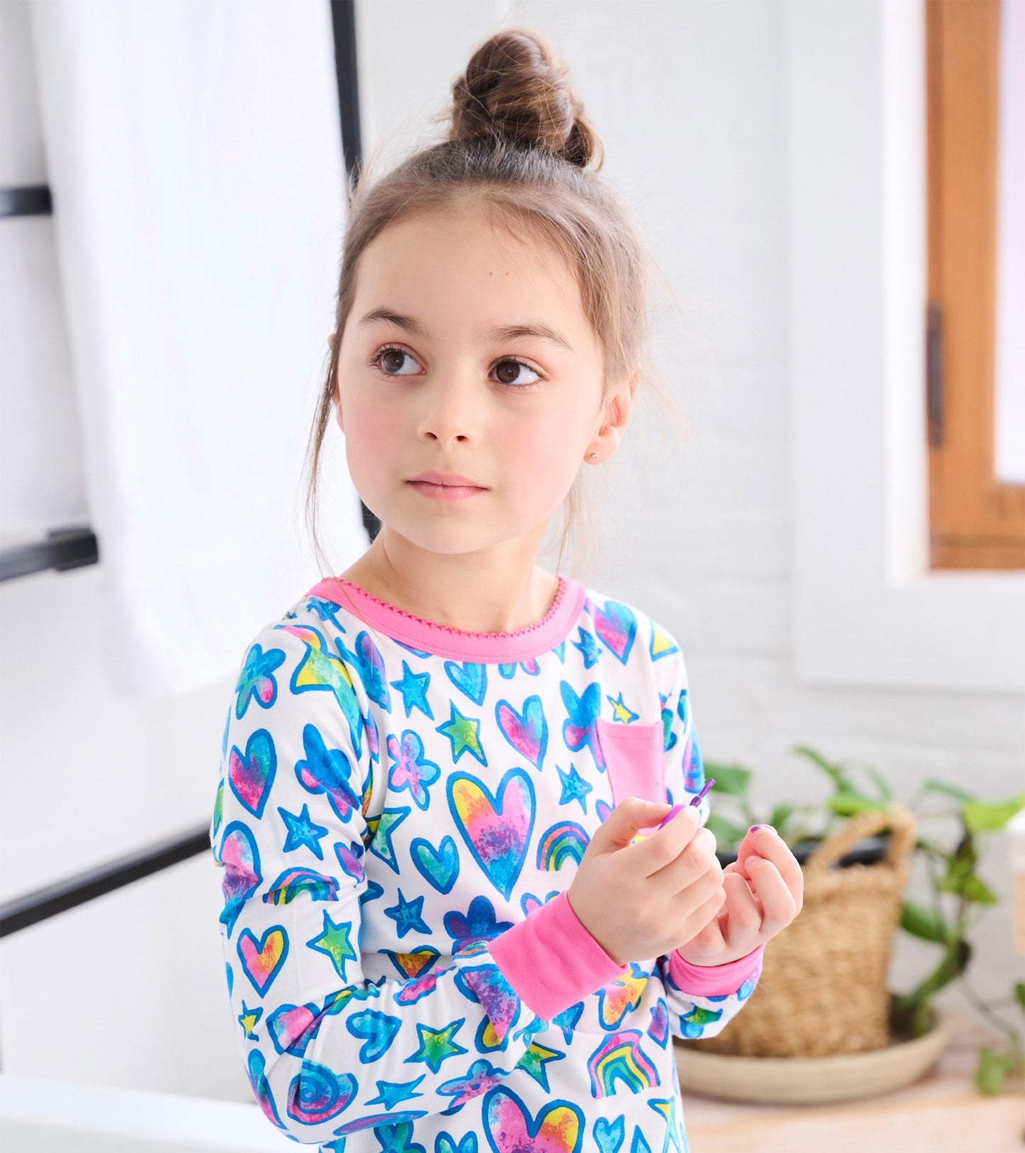 Bamboo pyjama set featuring colorful watercolour doodles of hearts, stars, and rainbows with pink trim and long sleeves.
