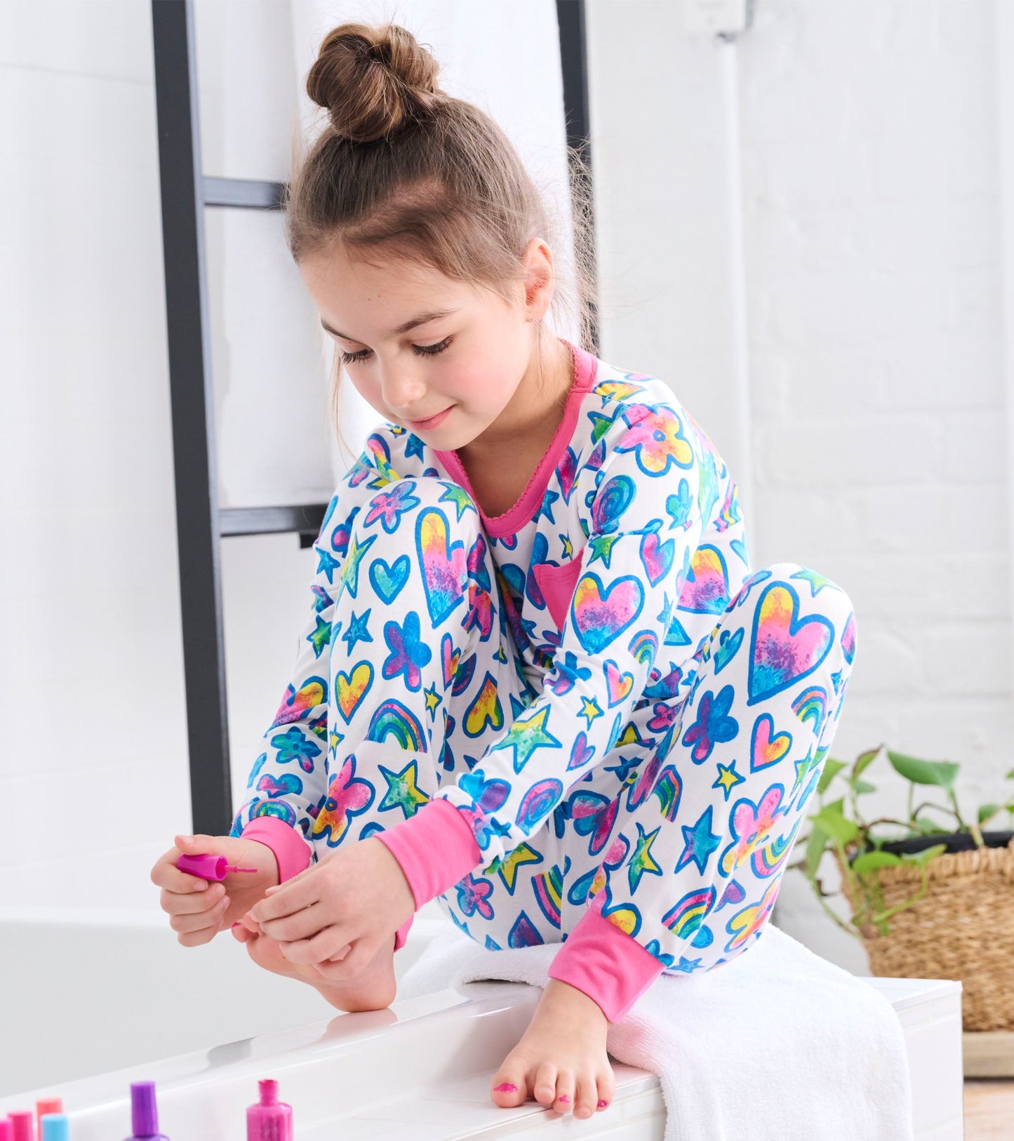 Bamboo pyjama set featuring colorful watercolour doodles of hearts, stars, and flowers with pink cuffs and neckline.