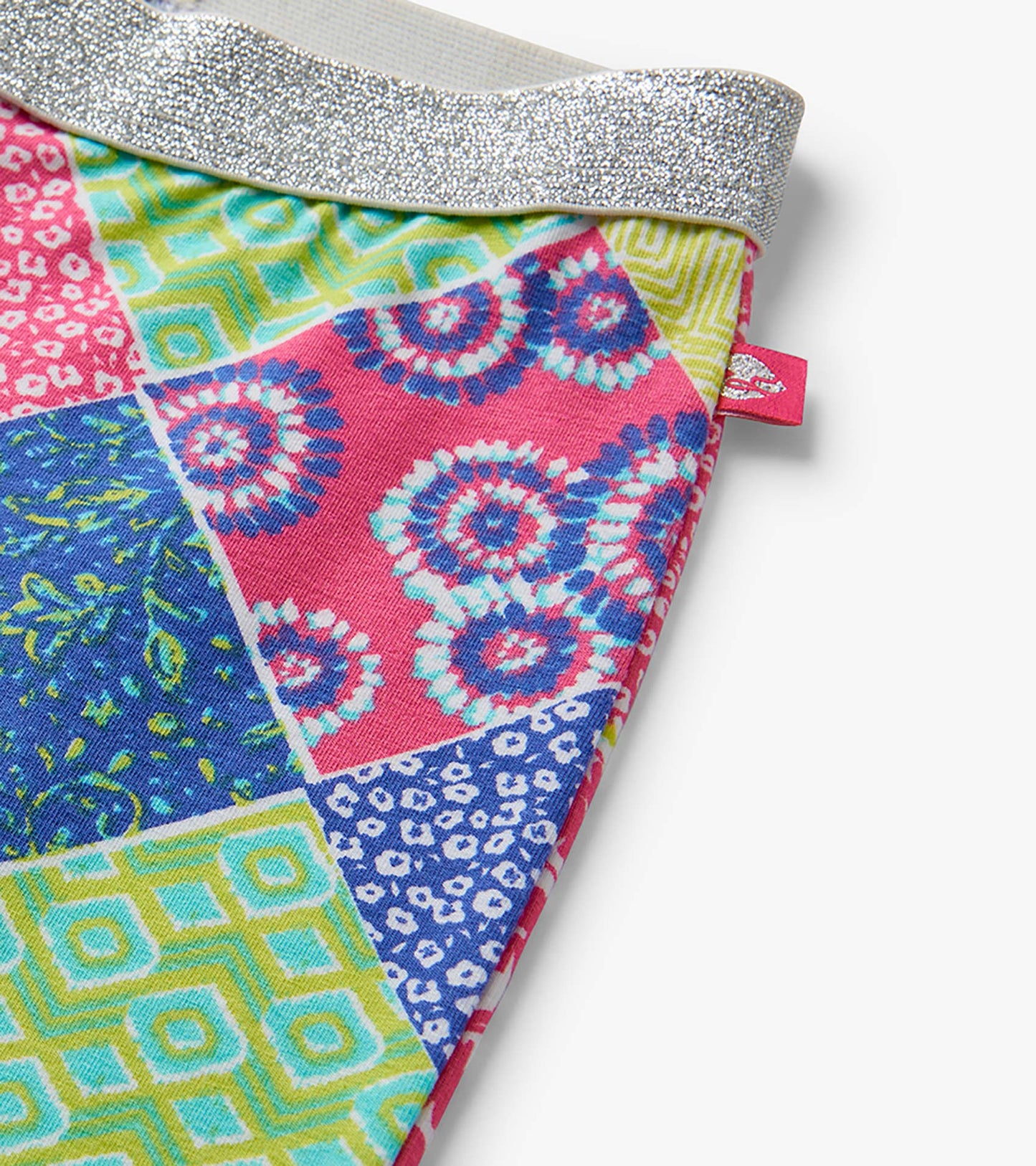 Colorful patchwork girls bell-bottom pants with silver glitter waistband, close-up detail