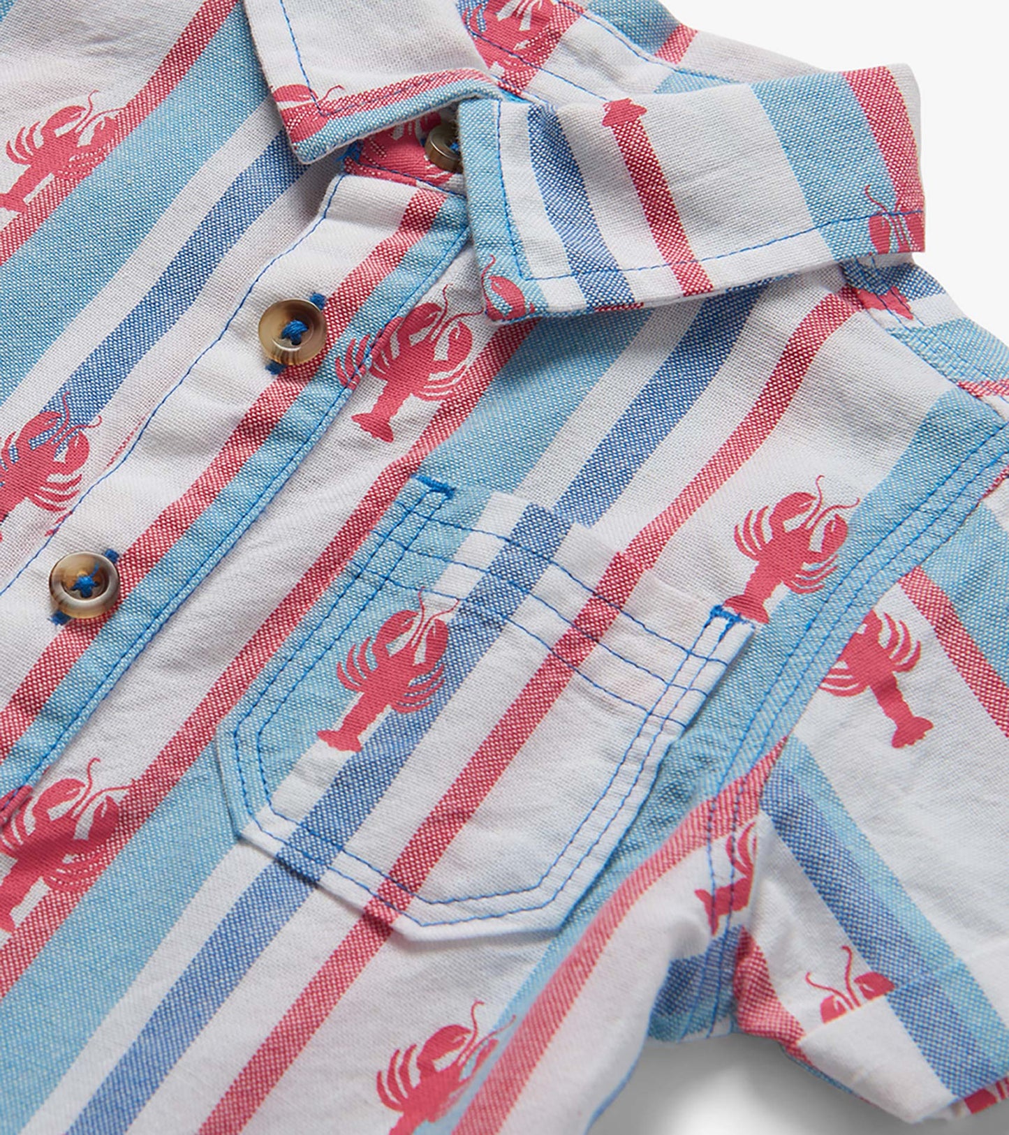 Close-up of a white woven baby romper with blue and red stripes, pink lobster print, and button front pocket.