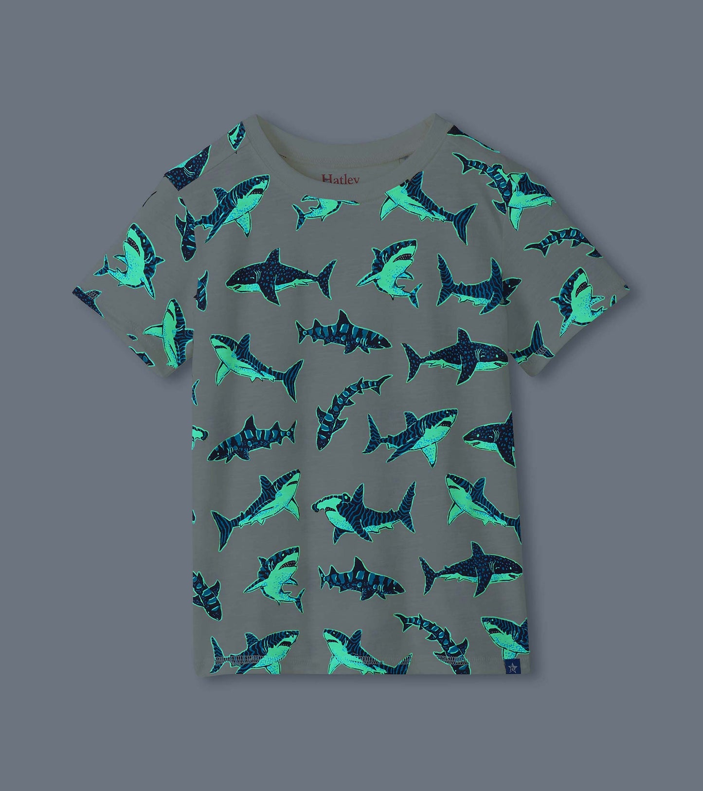 Boys shark print tee shown glowing in the dark, with bright blue and green shark outlines