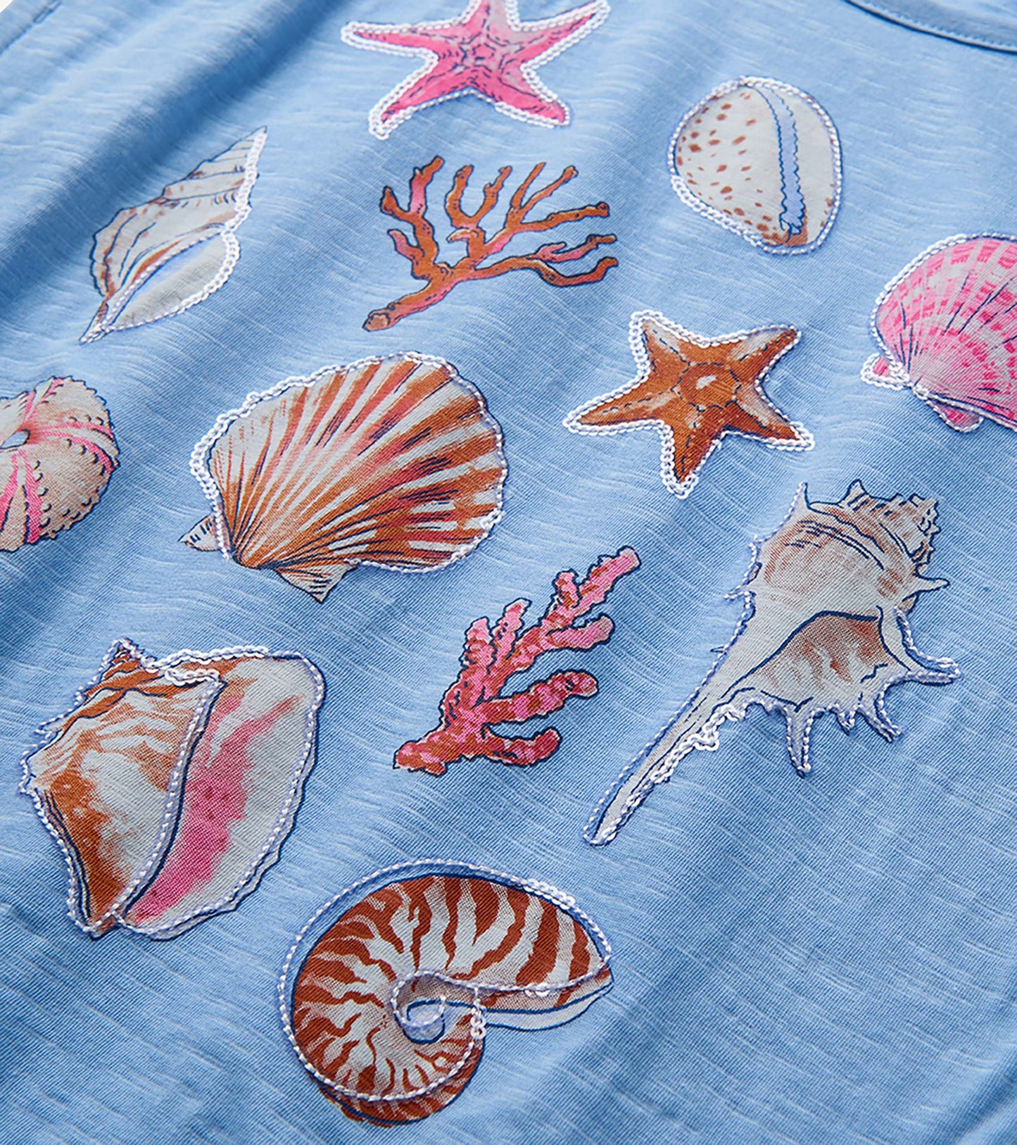 Light blue girls top with colorful seashell and starfish print, close-up view