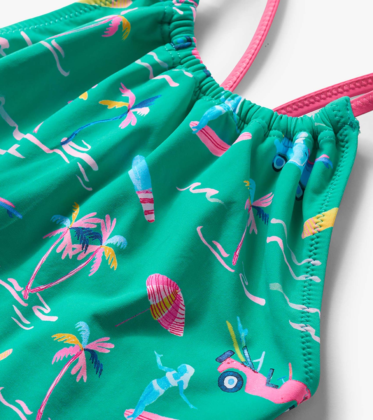 Green girls’ one-piece swimsuit with colorful tropical print and pink straps, close-up front view
