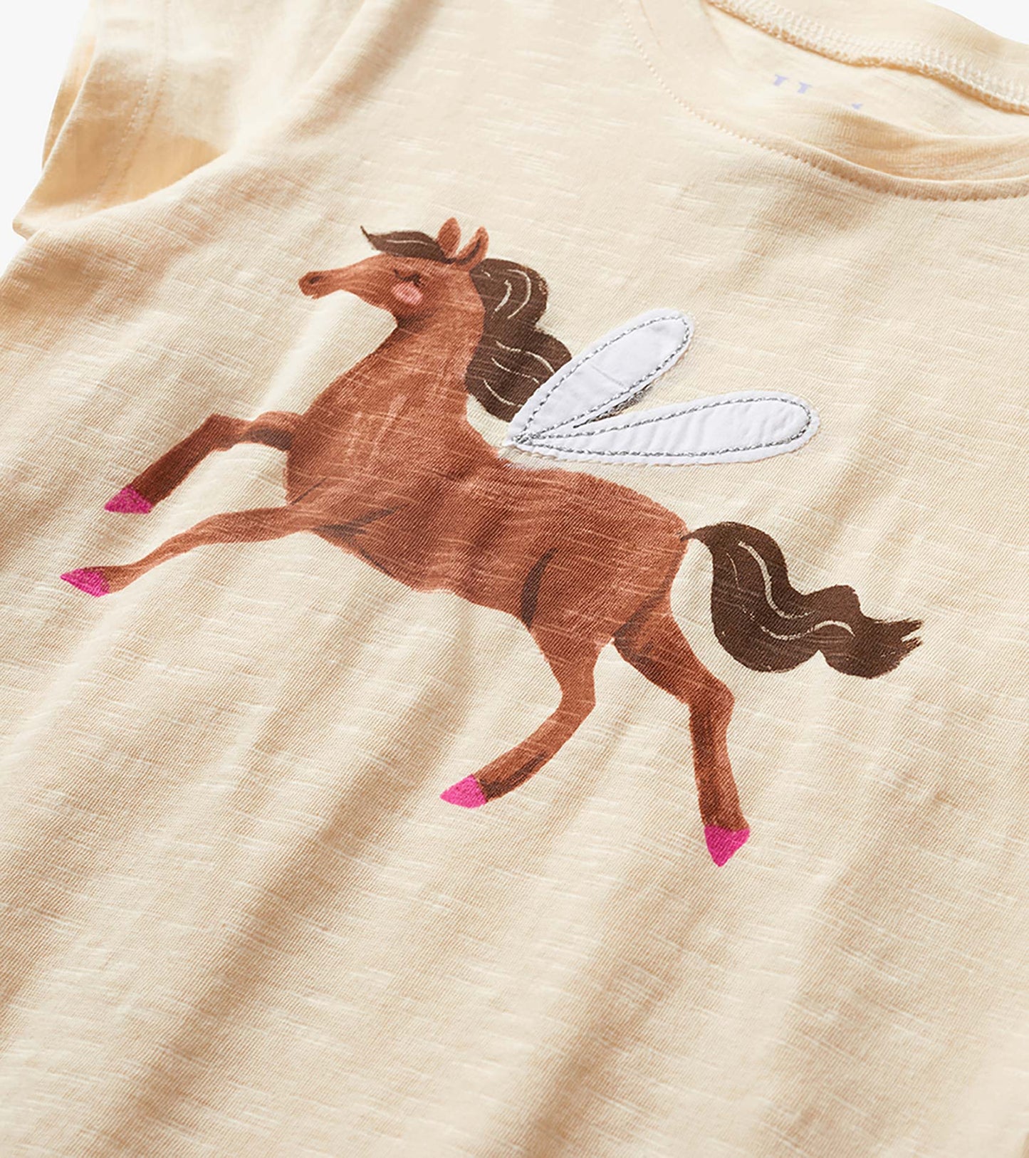 Cream toddler T-shirt with a brown winged horse graphic and pink hooves, close-up front view
