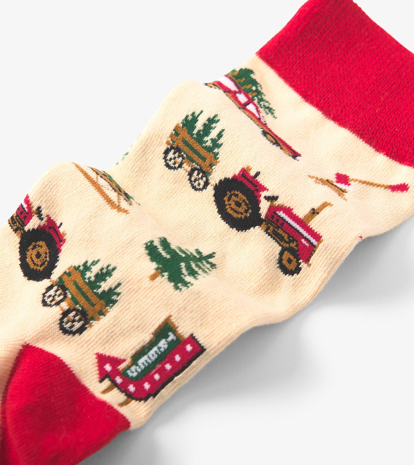 Beige crew socks featuring red accents and festive patterns of tractors, trees, and Christmas-themed elements.
