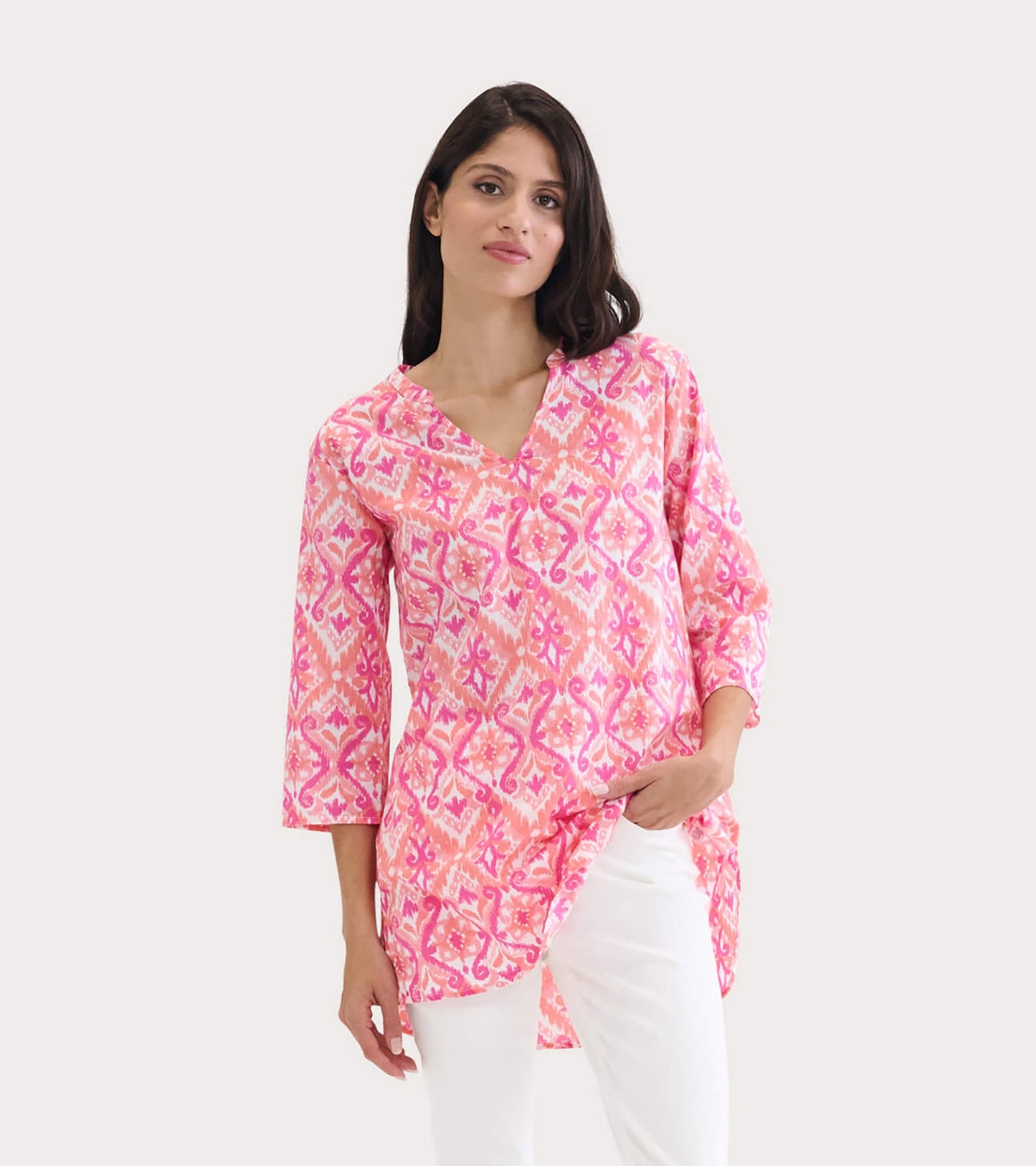 Pink ikat tunic with a V-neck and three-quarter sleeves, styled with white pants.