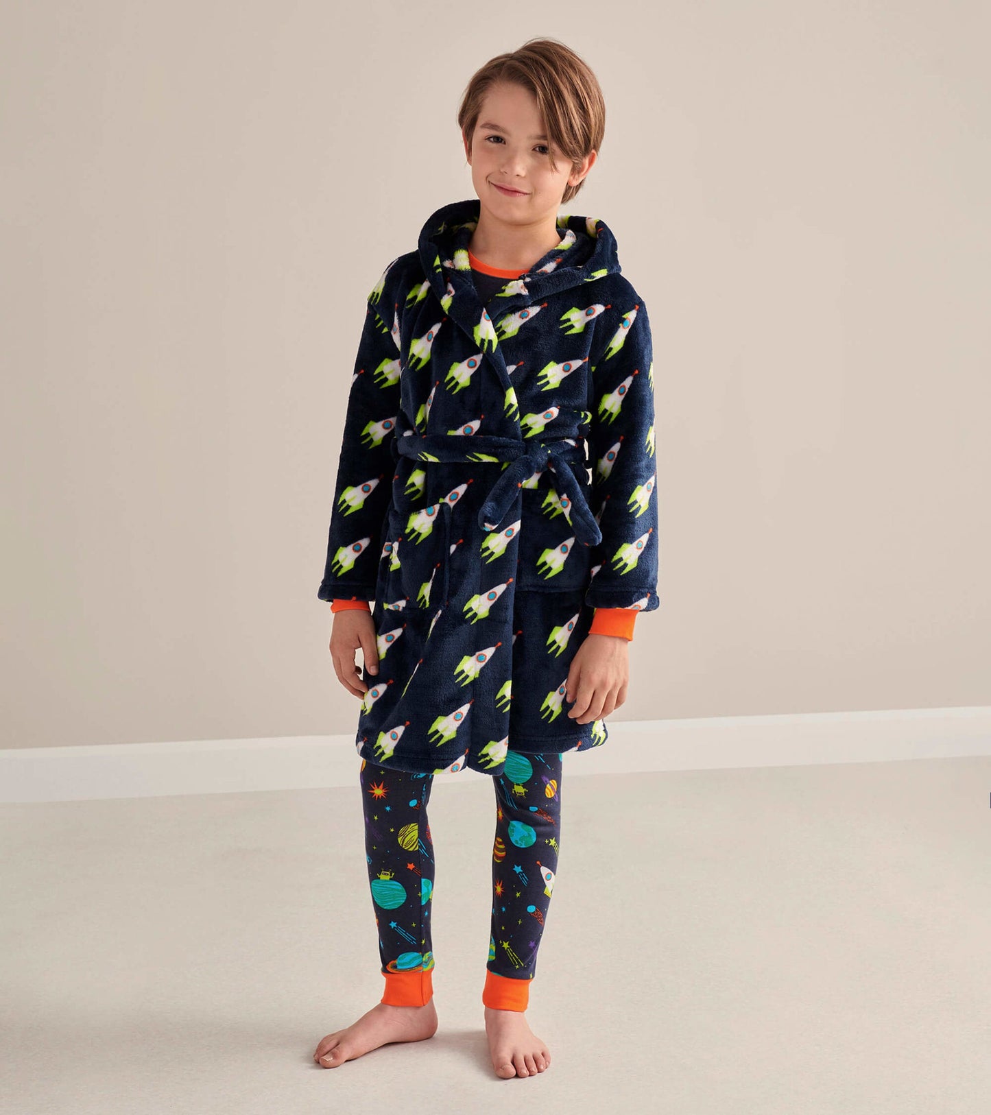 Navy fleece robe with rocket pattern, featuring a hood and orange cuffs, worn by a child over space-themed leggings.