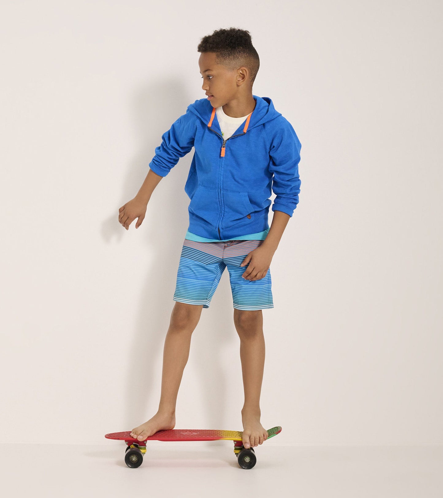 Boys' quick-dry shorts in blue with horizontal stripes, worn while skateboarding.