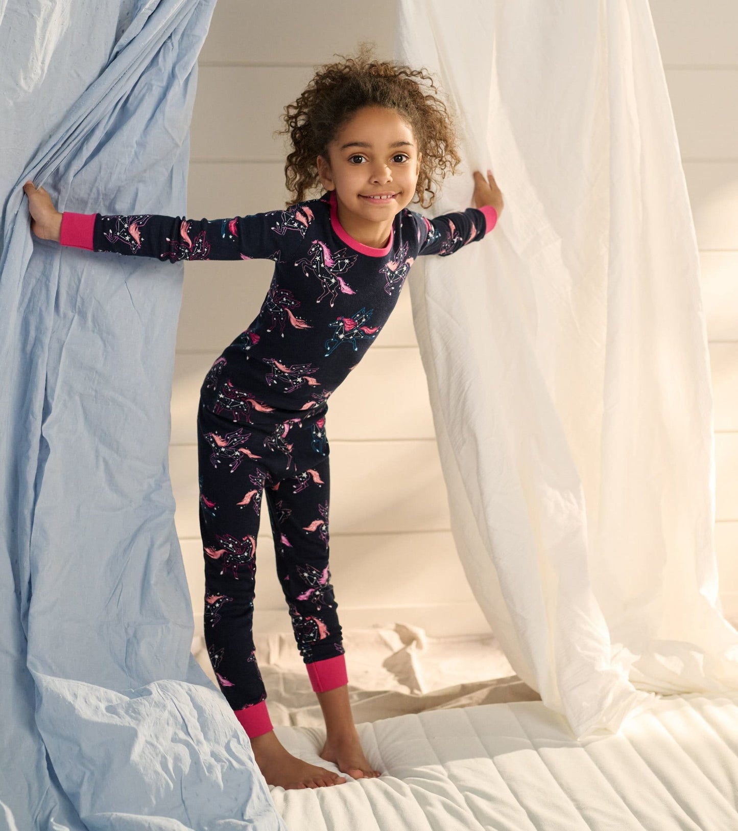 Navy organic cotton pyjama set featuring unicorn constellations and pink cuffs, designed for kids.