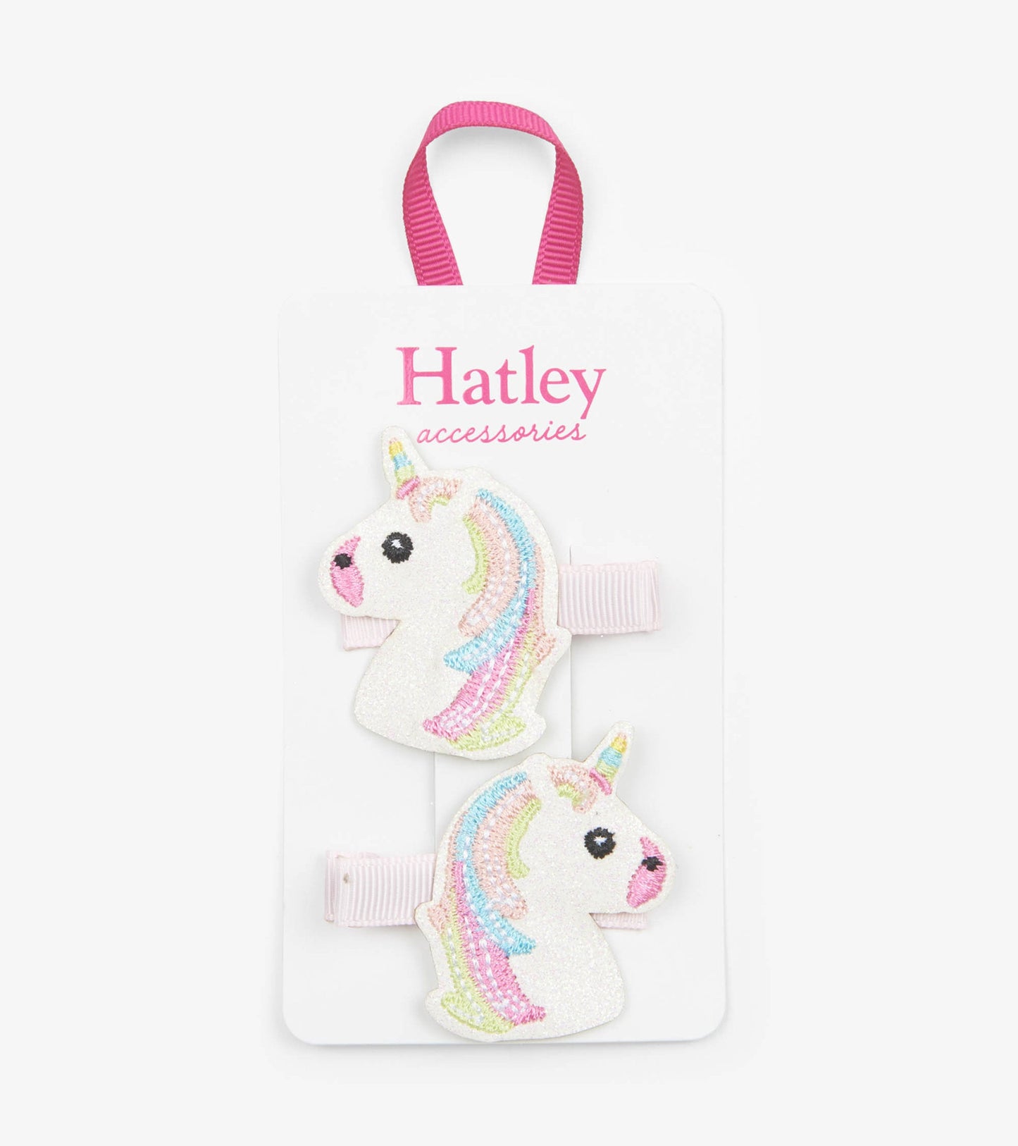 Glittery unicorn hair clips with pastel rainbow manes on a pink elastic band, displayed on a white card.
