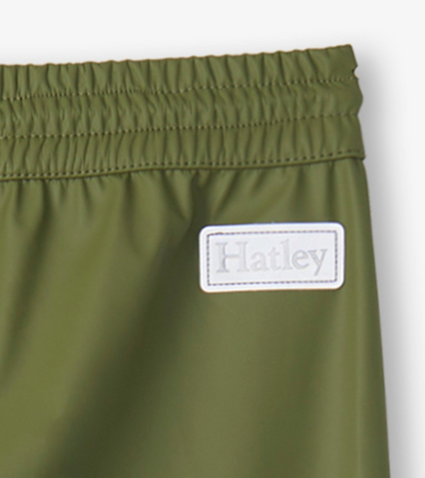 Forest green kids' rain pants with an elastic waistband and a small label. Suitable for outdoor play in wet weather.