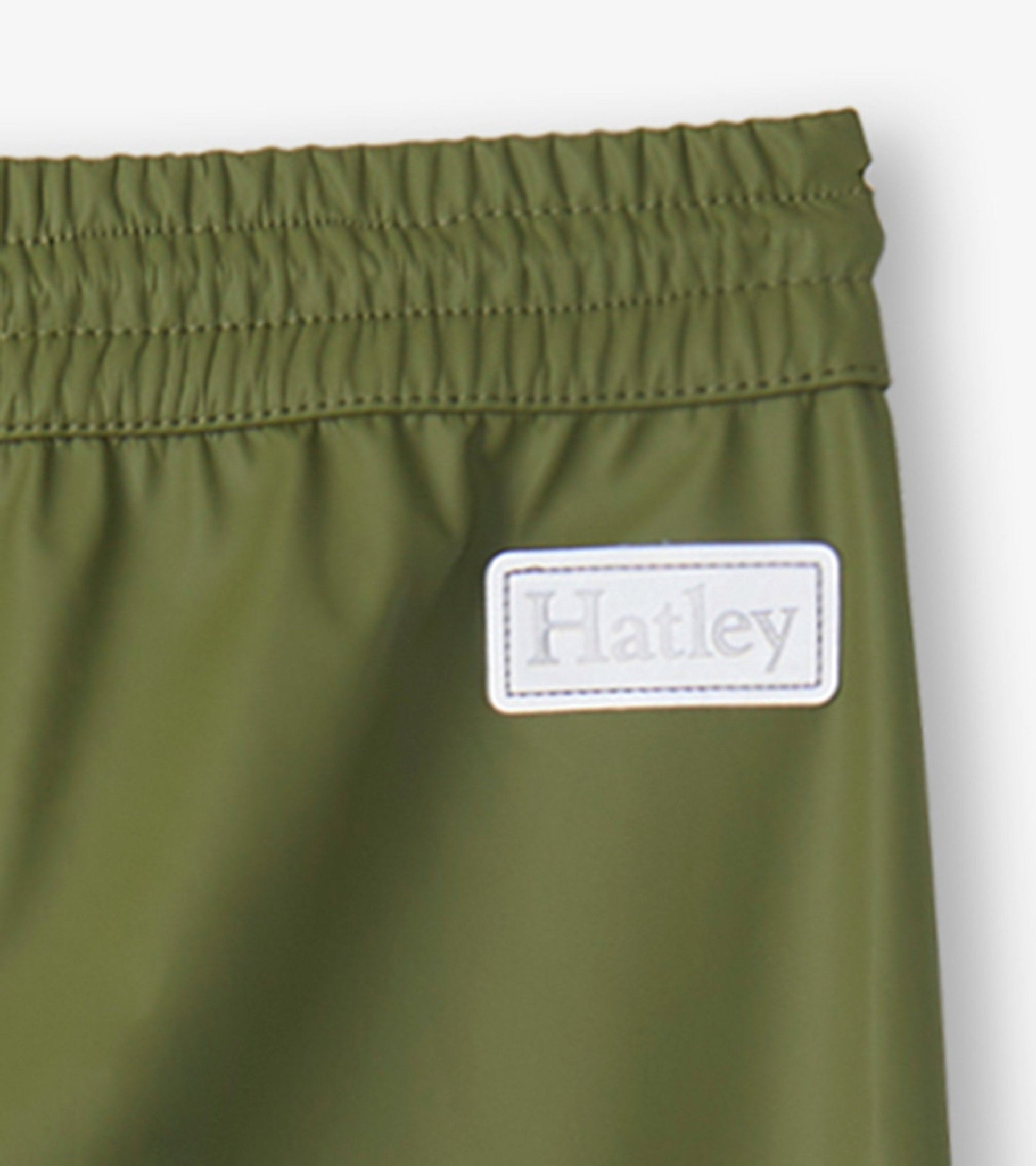 Forest green kids' rain pants with an elastic waistband and a small label. Suitable for outdoor play in wet weather.