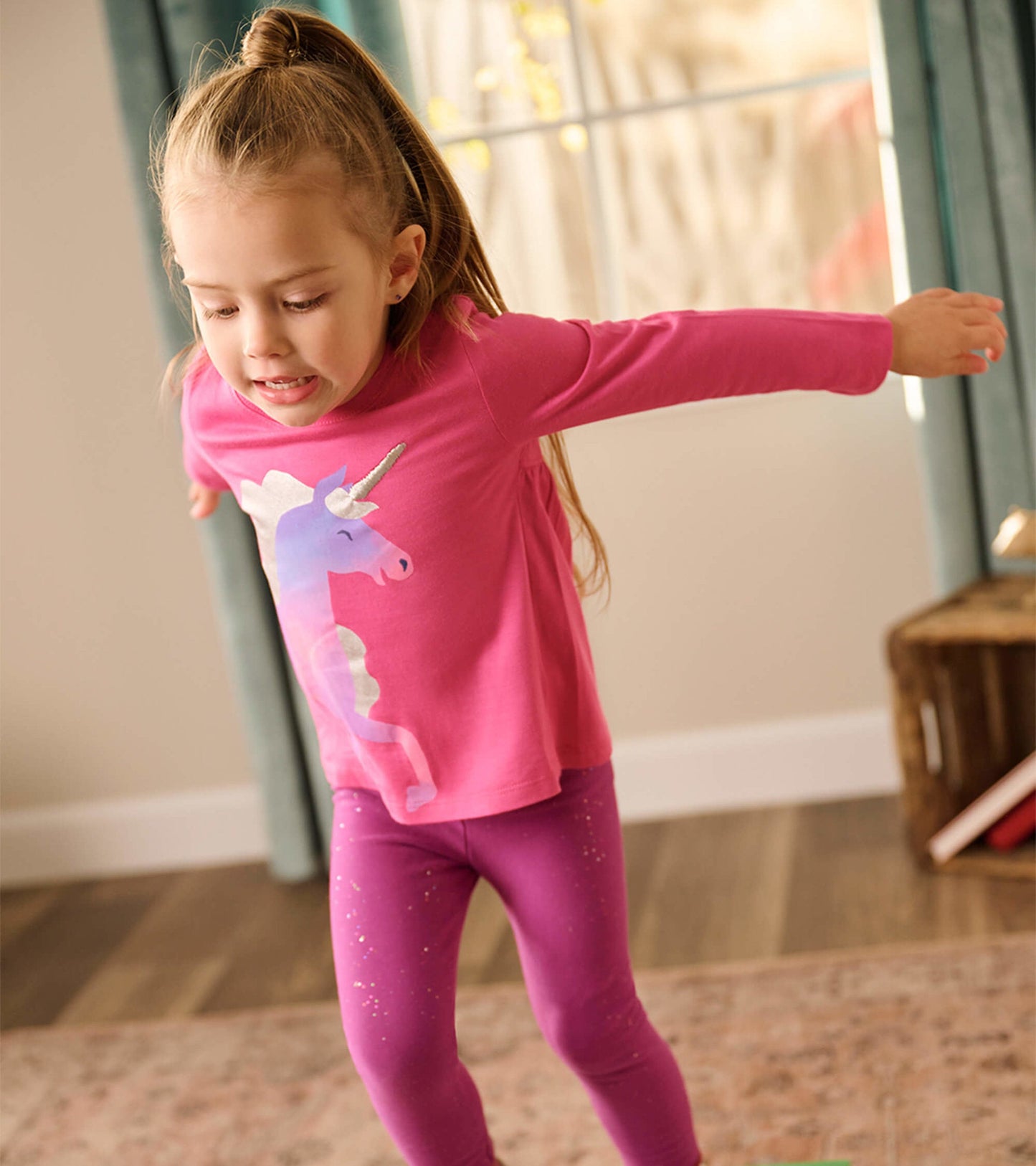 Raspberry long sleeve t-shirt featuring a colorful unicorn graphic, paired with purple leggings.