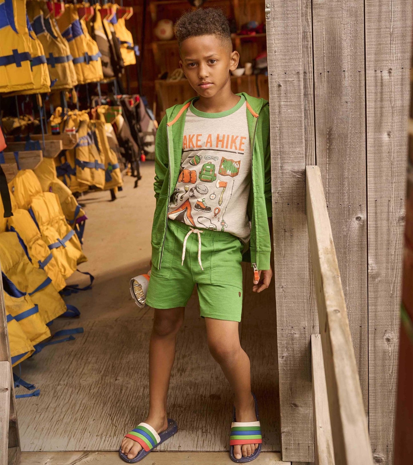 Green relaxed shorts with an elastic waistband, paired with a graphic tee and sandals, suitable for outdoor activities.