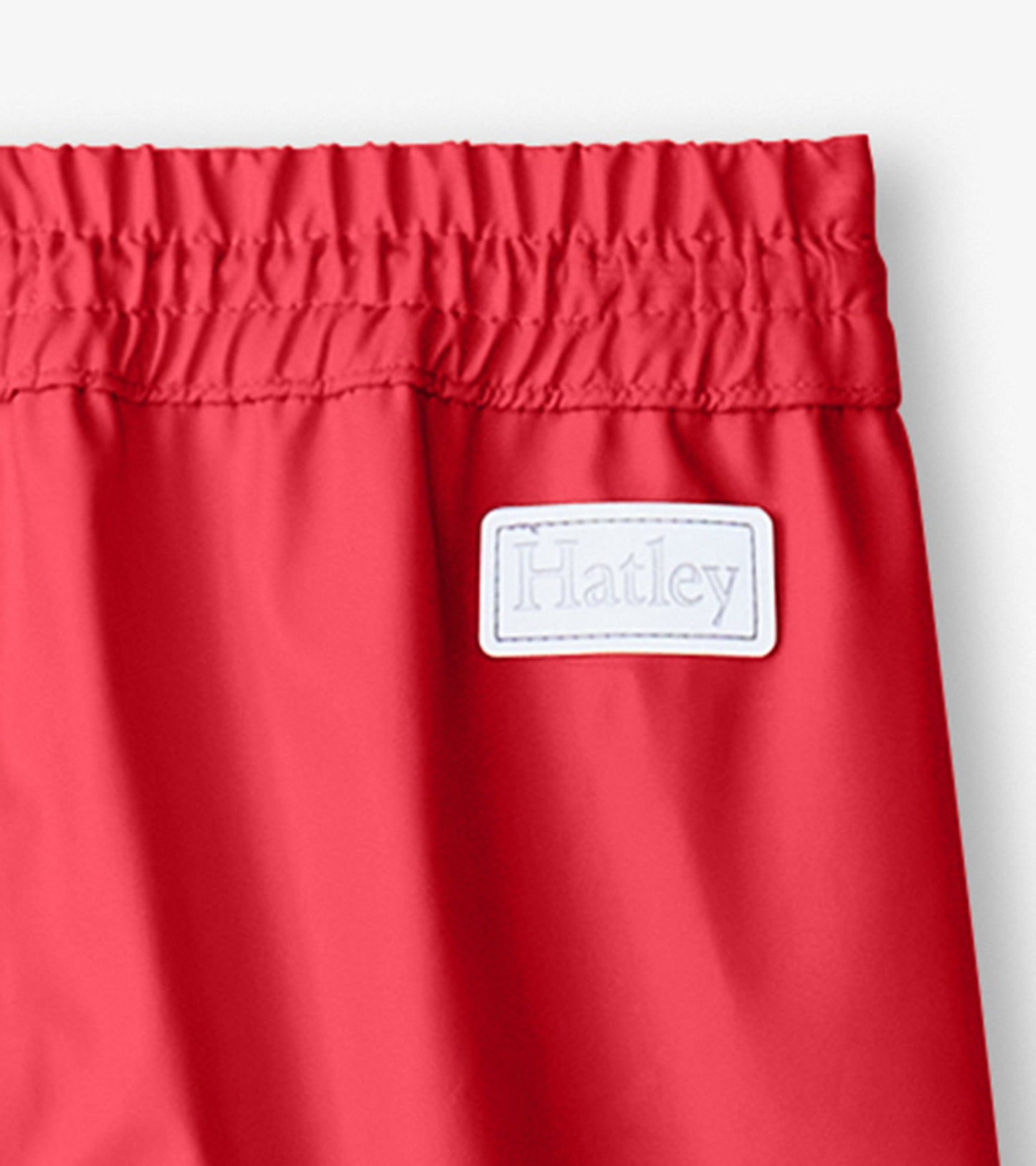 Red waterproof kids' rain pants with an elastic waistband and a tag on the side.