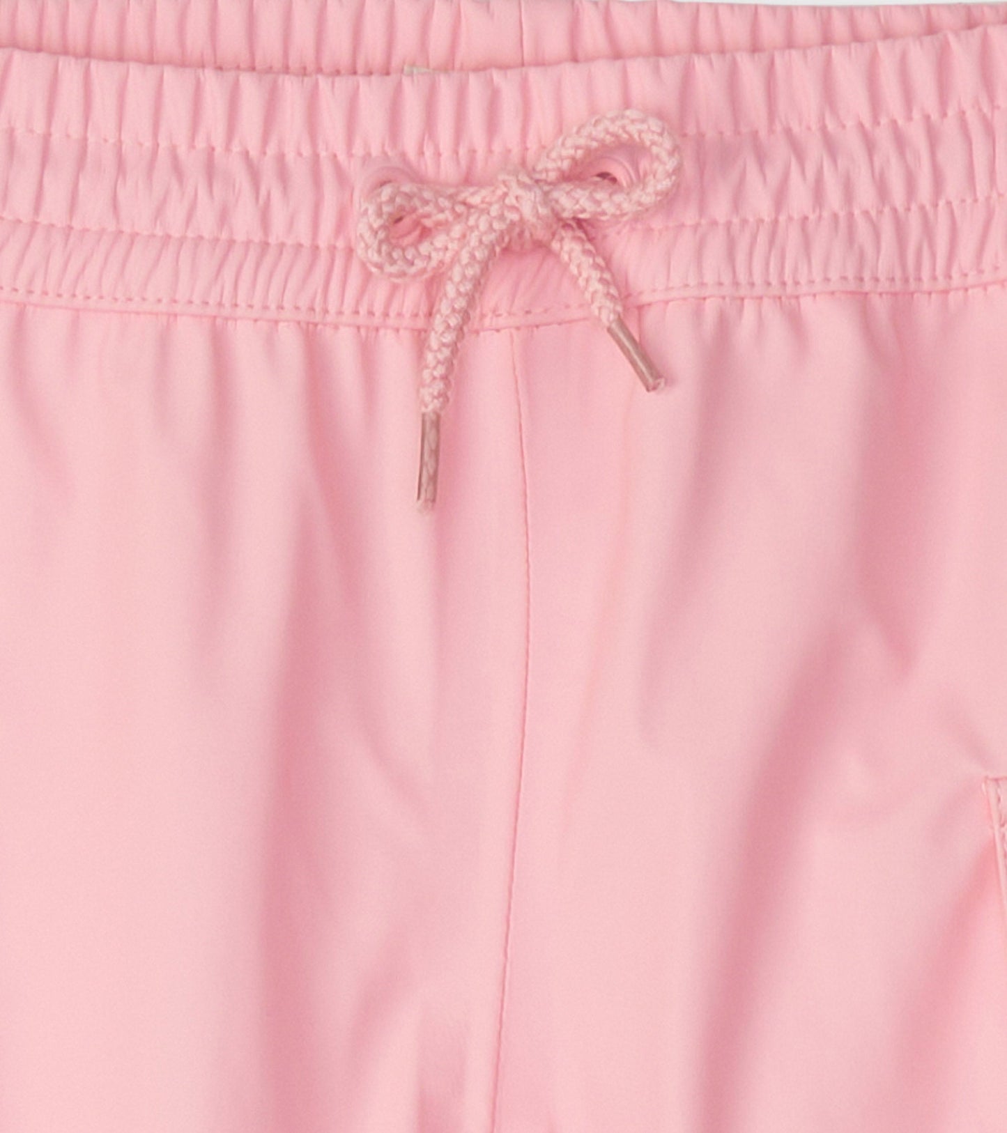Light pink kids' rain pants with an elastic waistband and drawstring detail, suitable for outdoor play.