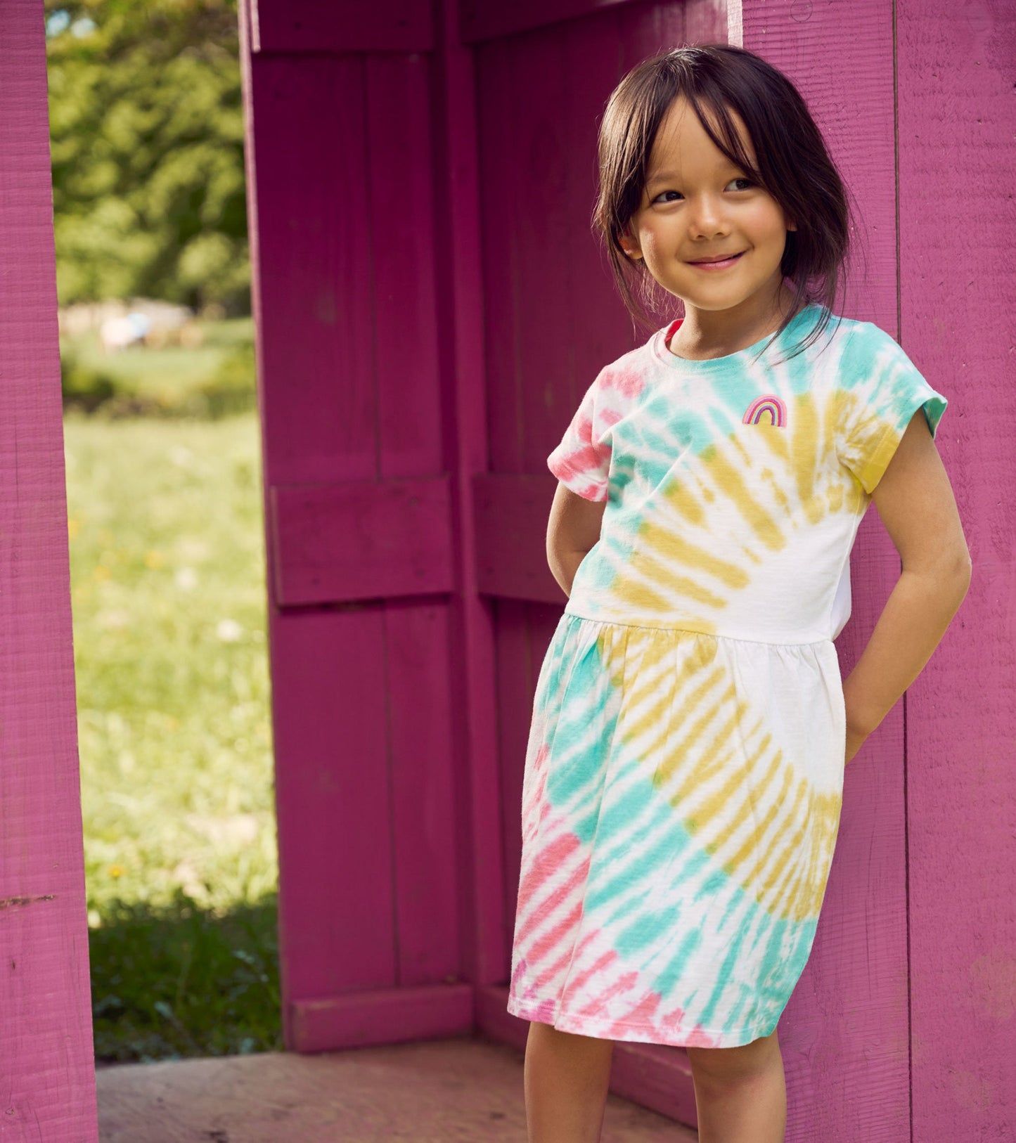 Short-sleeved skater dress featuring a colorful tie-dye pattern in pink, yellow, and turquoise, with a relaxed fit.
