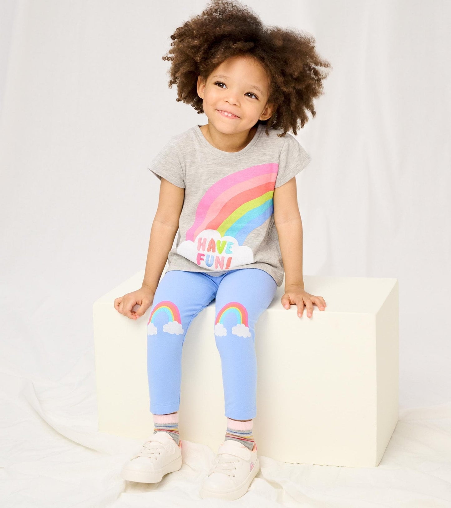 Gray toddler tee with rainbow graphic, paired with light blue leggings featuring rainbow and cloud designs.