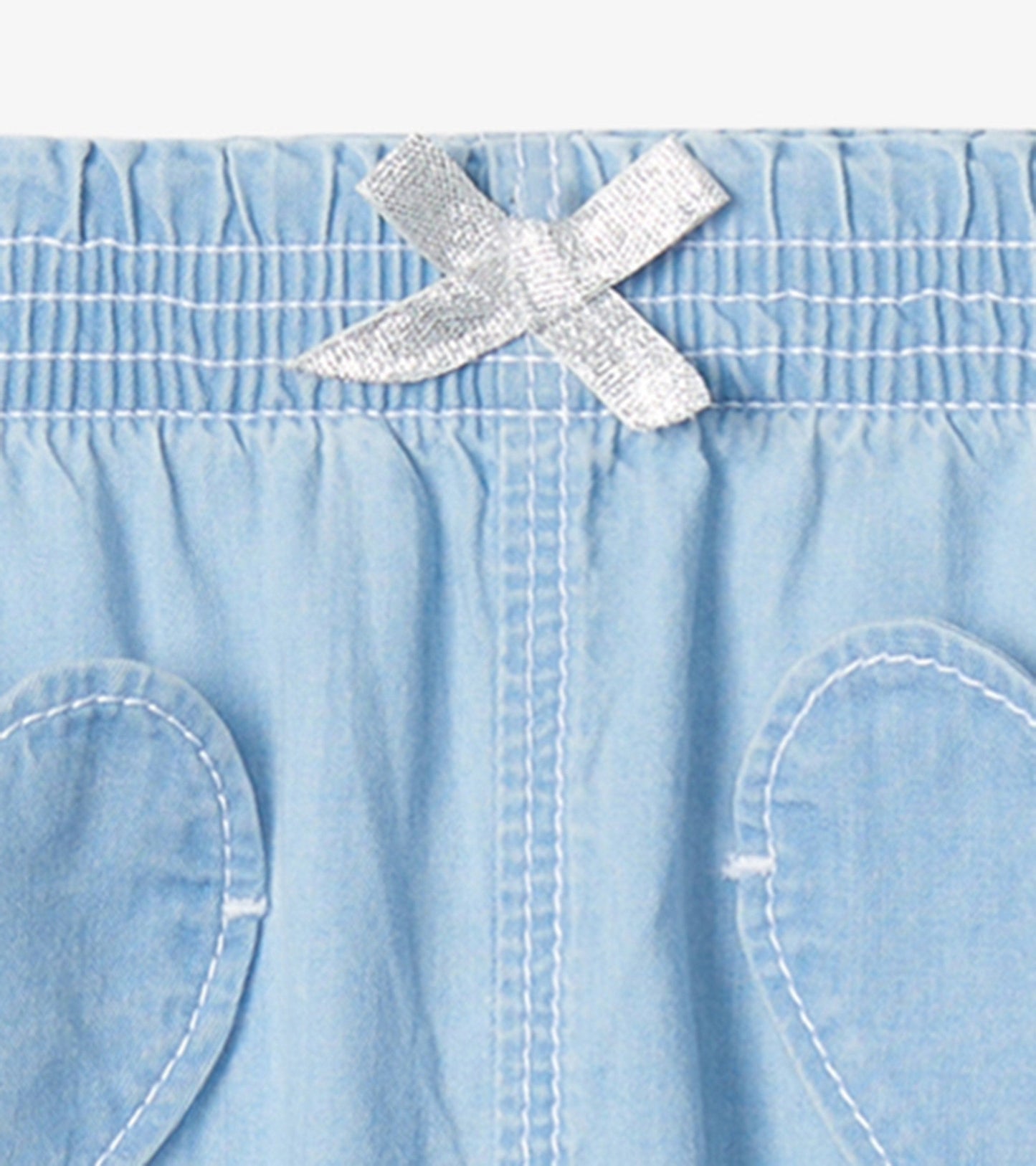 Light blue denim baggy pants for baby and toddler girls, featuring a silver bow detail and heart-shaped pockets.