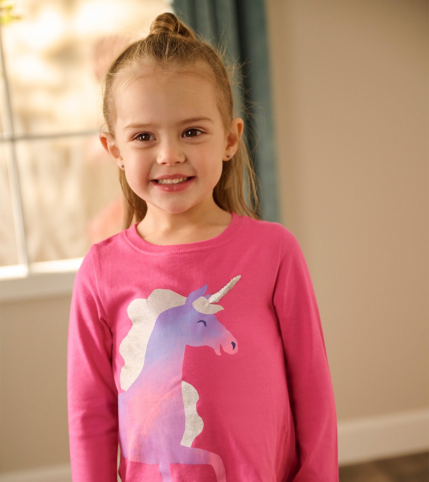 Pink long sleeve t-shirt featuring a unicorn graphic in pastel colors, suitable for young children.