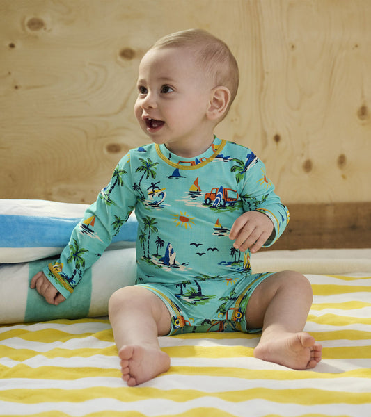 Light blue long-sleeve one-piece rashguard featuring a colorful beach scene with palm trees, boats, and sun motifs.