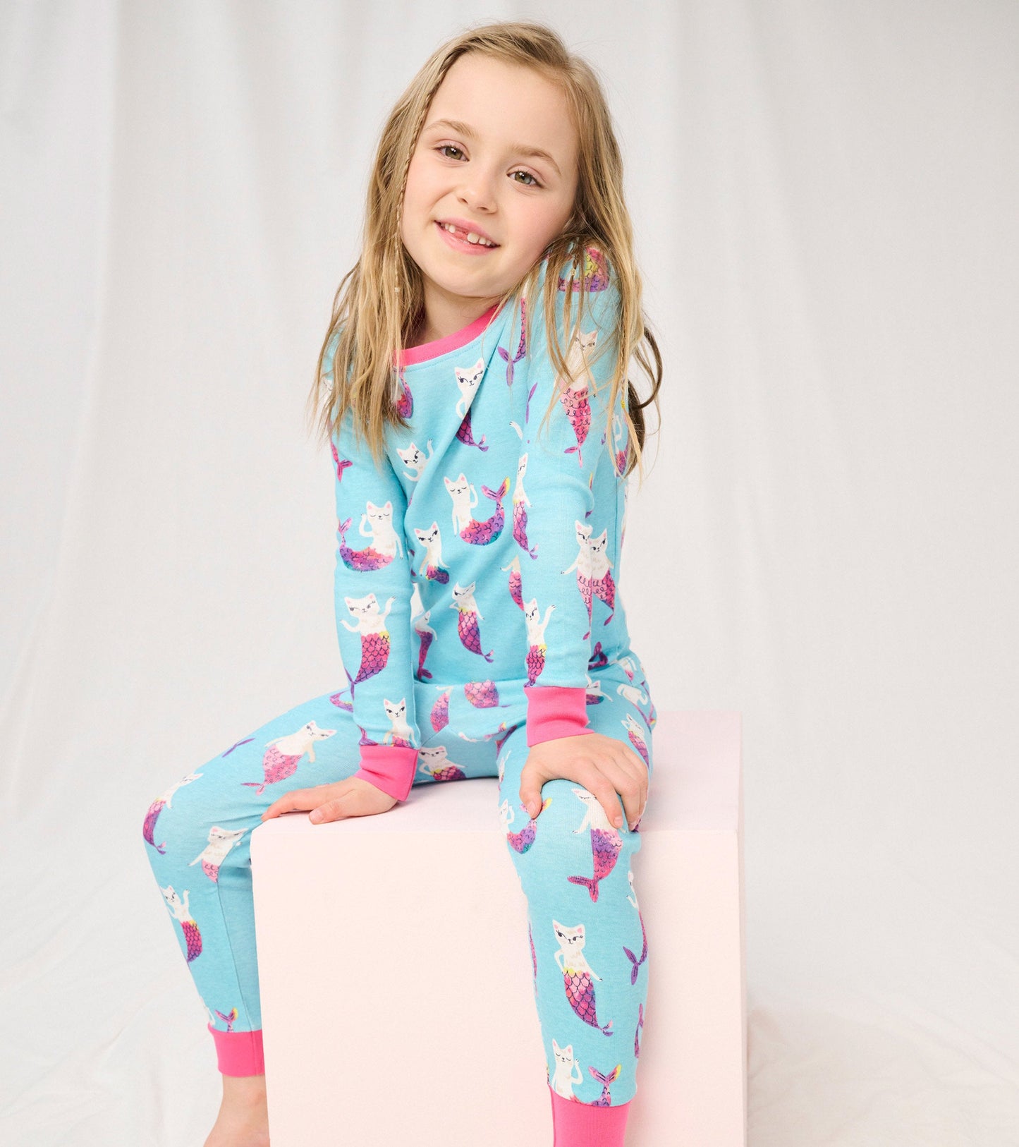 Light blue pajama set featuring mermaid cats, with pink cuffs and neckline, suitable for kids.