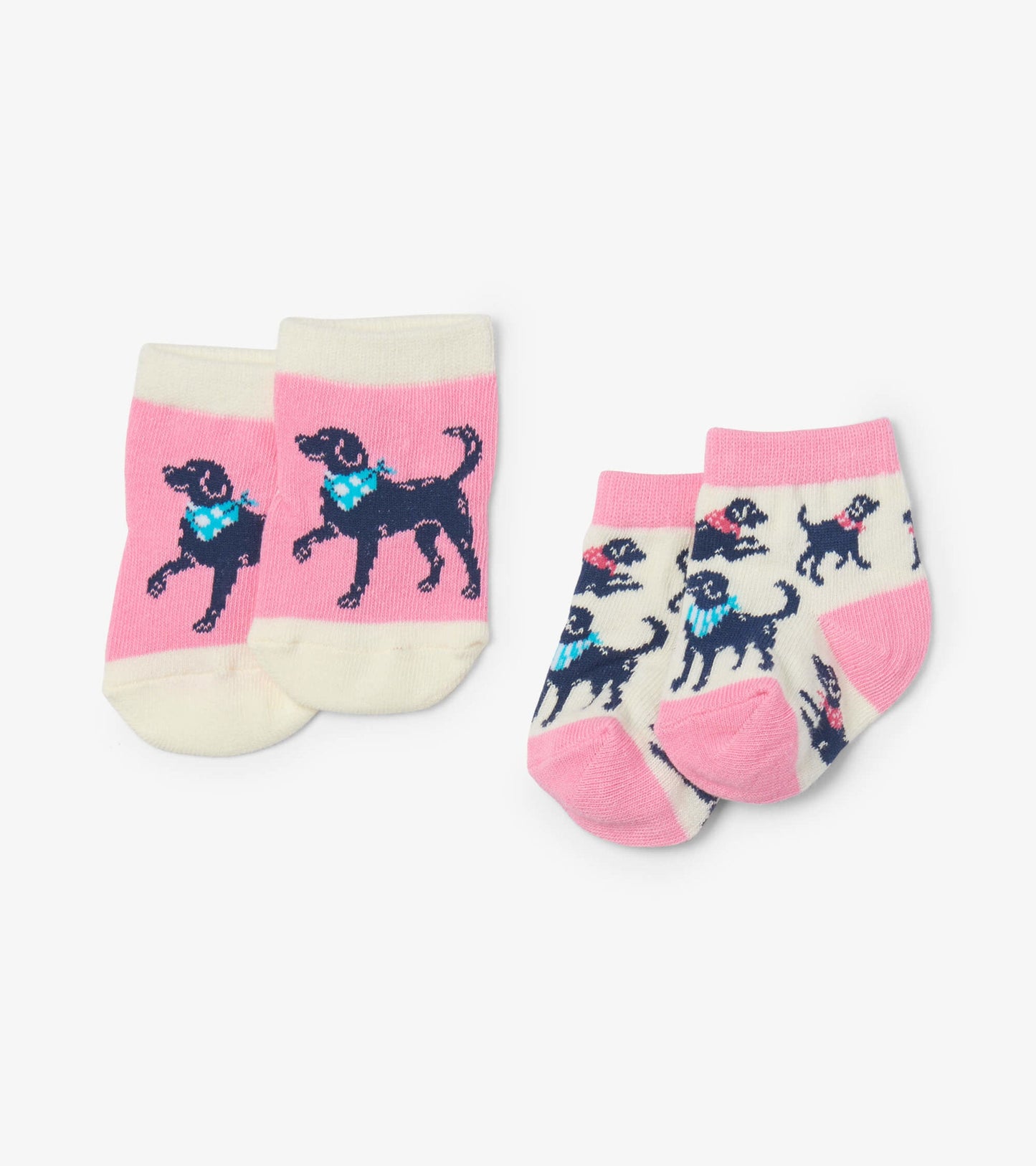 Two pairs of baby socks: one pink with a black dog design, the other cream with multiple black dogs, both in soft cotton.
