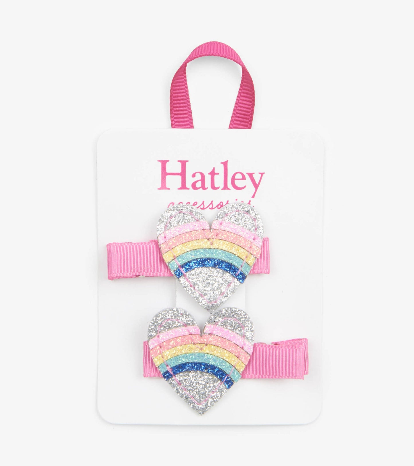 Glittery heart-shaped hair clips in rainbow colors with pink ribbon bands, displayed on a card.