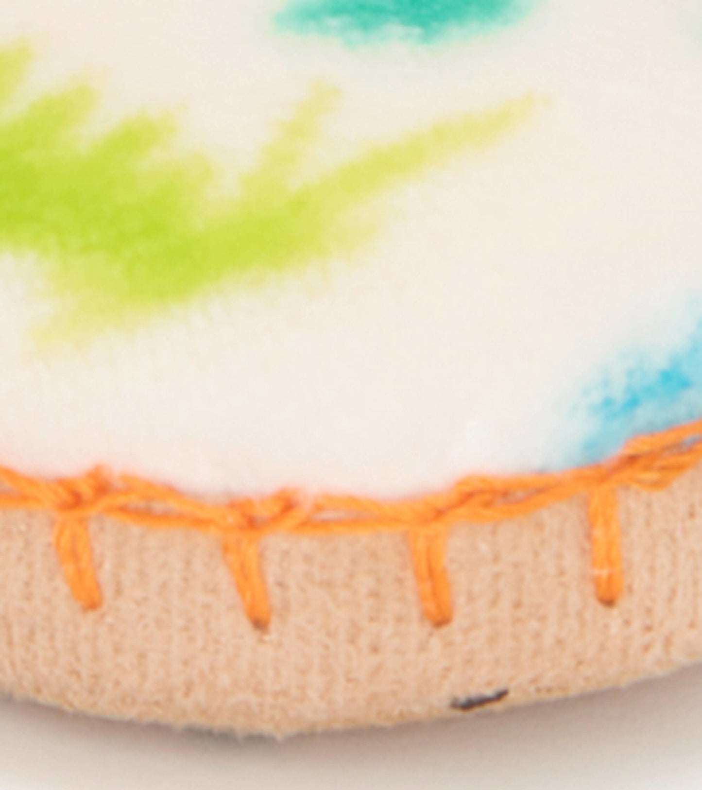 Fleece slippers featuring a colorful dinosaur pattern with an orange stitched edge, ideal for kids' comfort.