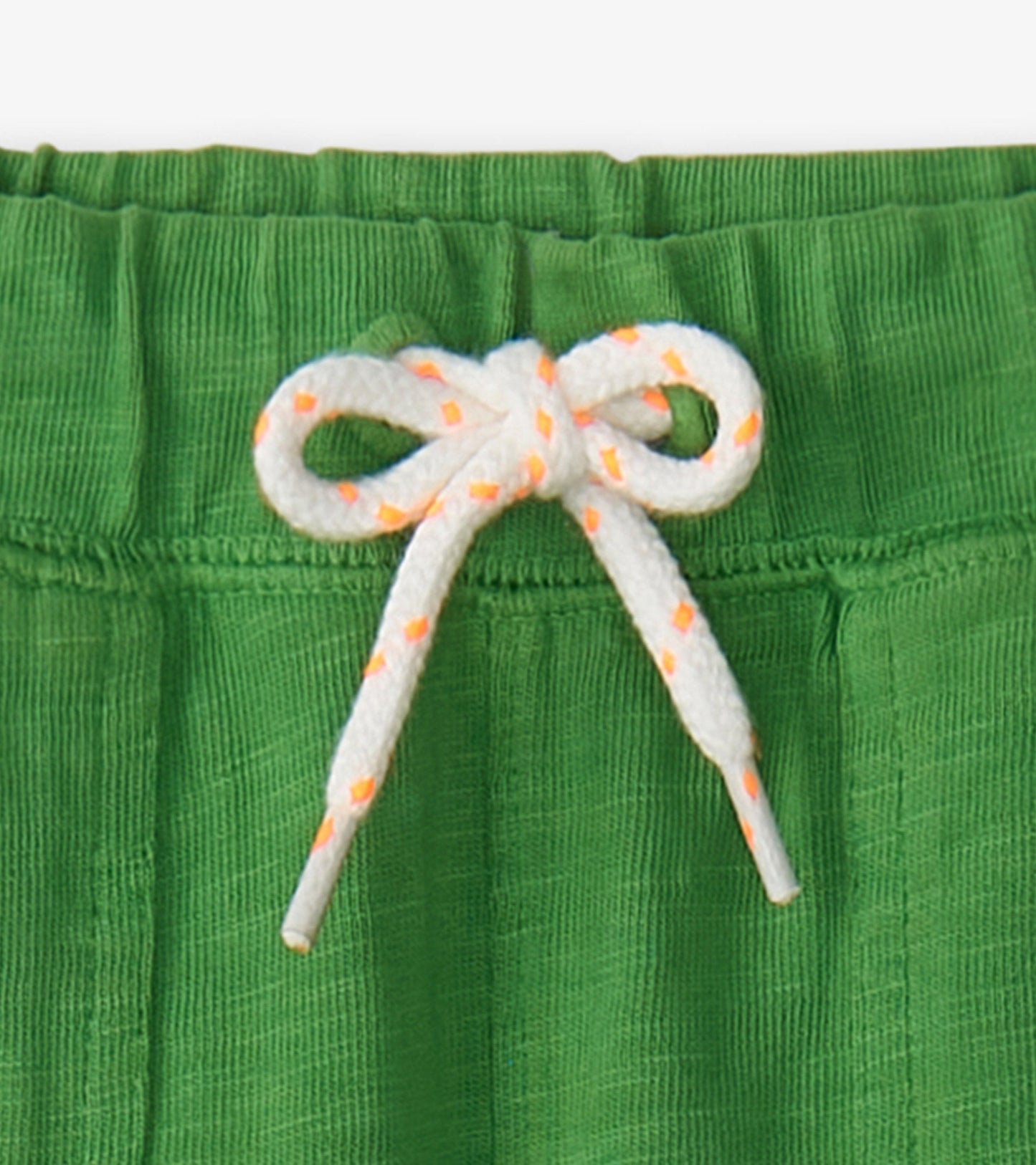 Green relaxed shorts with a textured fabric and a white drawstring with orange accents.