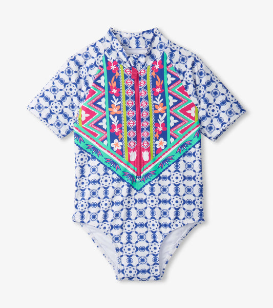 Short-sleeve one-piece rashguard featuring a vibrant blue and pink kaleidoscope pattern with a zip front.