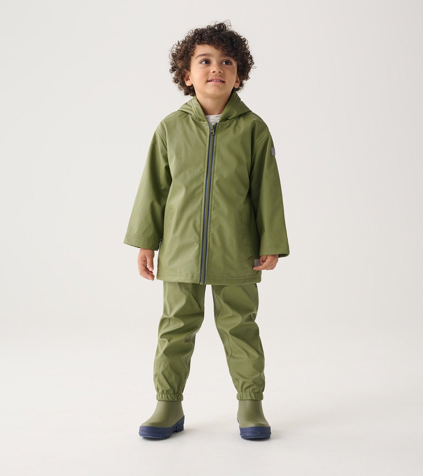 Forest green waterproof rain pants with elastic cuffs, paired with a matching jacket, suitable for kids.
