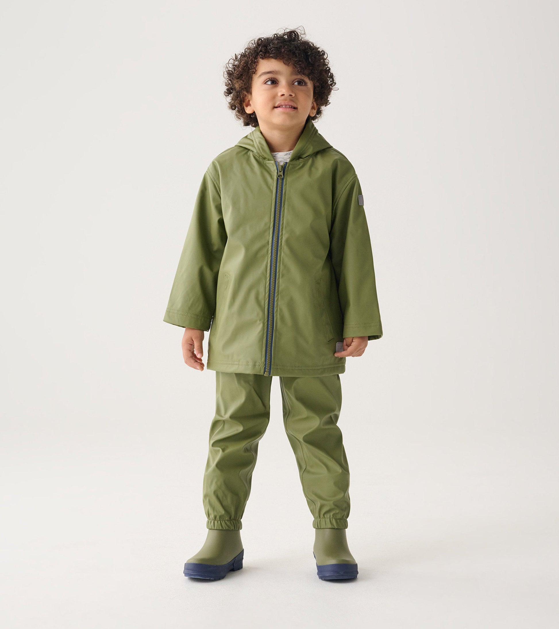 Forest green waterproof rain pants with elastic cuffs, paired with a matching jacket, suitable for kids.