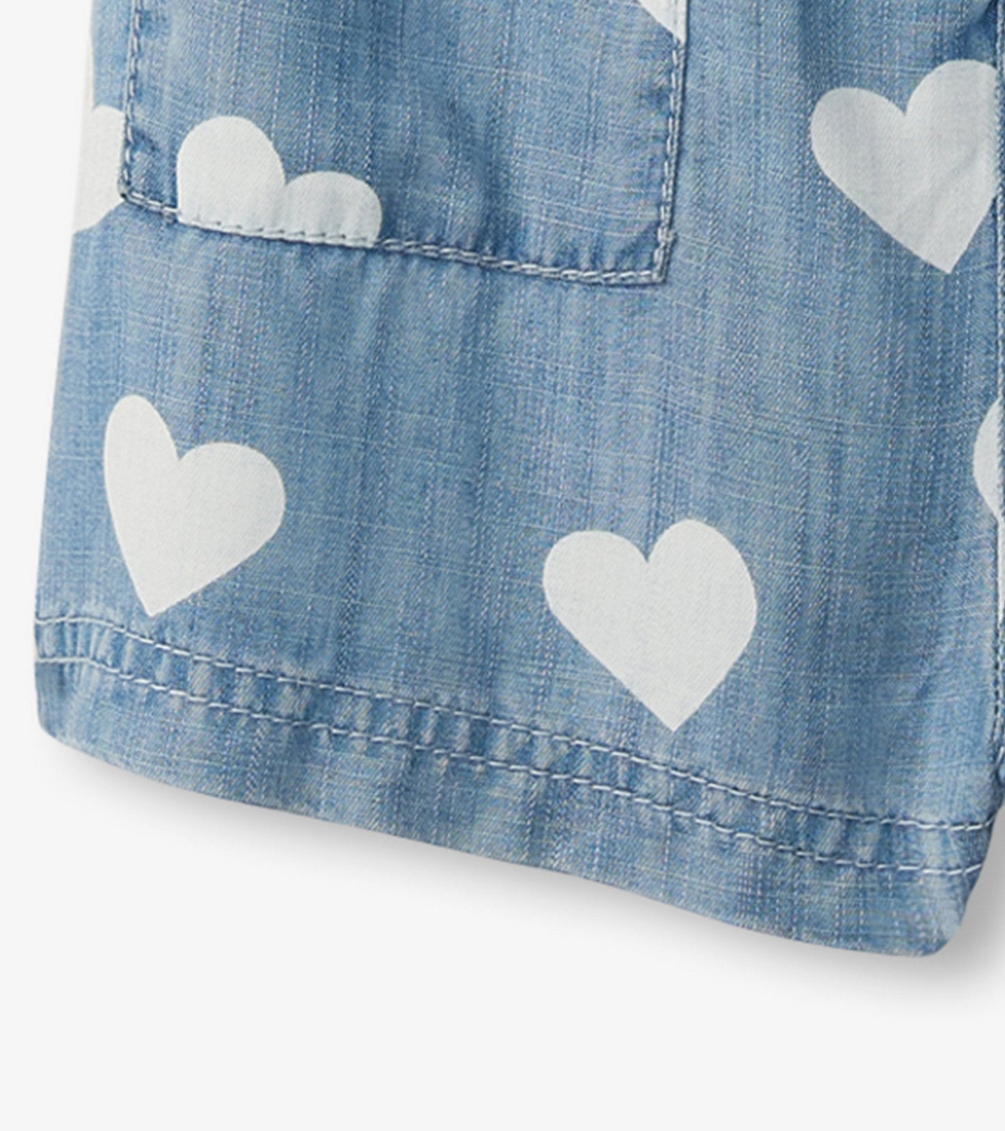 Light blue slouchy overalls with white heart patterns, featuring a pocket and a relaxed fit.