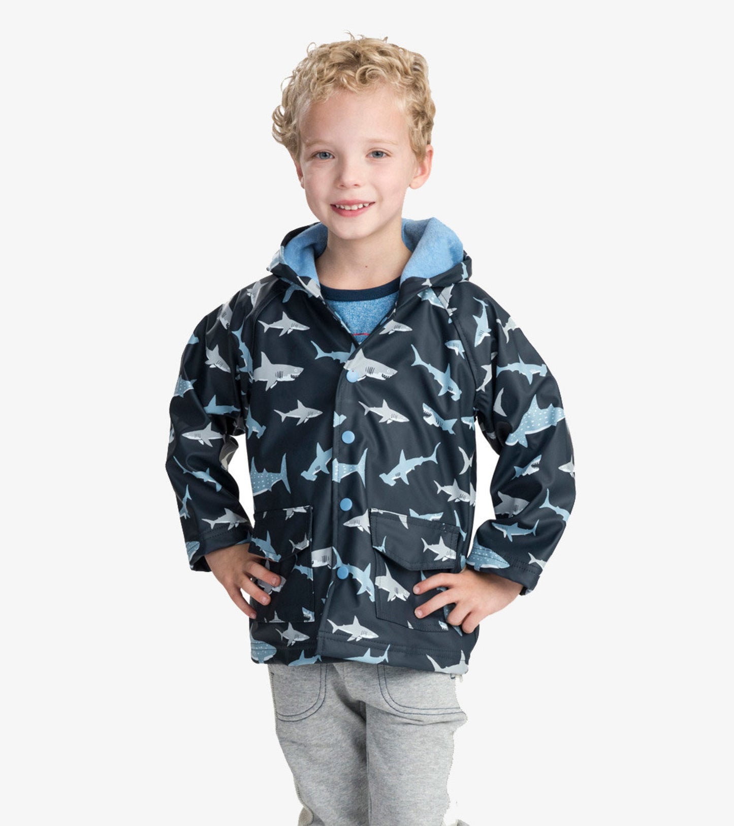 Navy raincoat featuring a shark pattern, with a hood and front pockets, worn by a child.