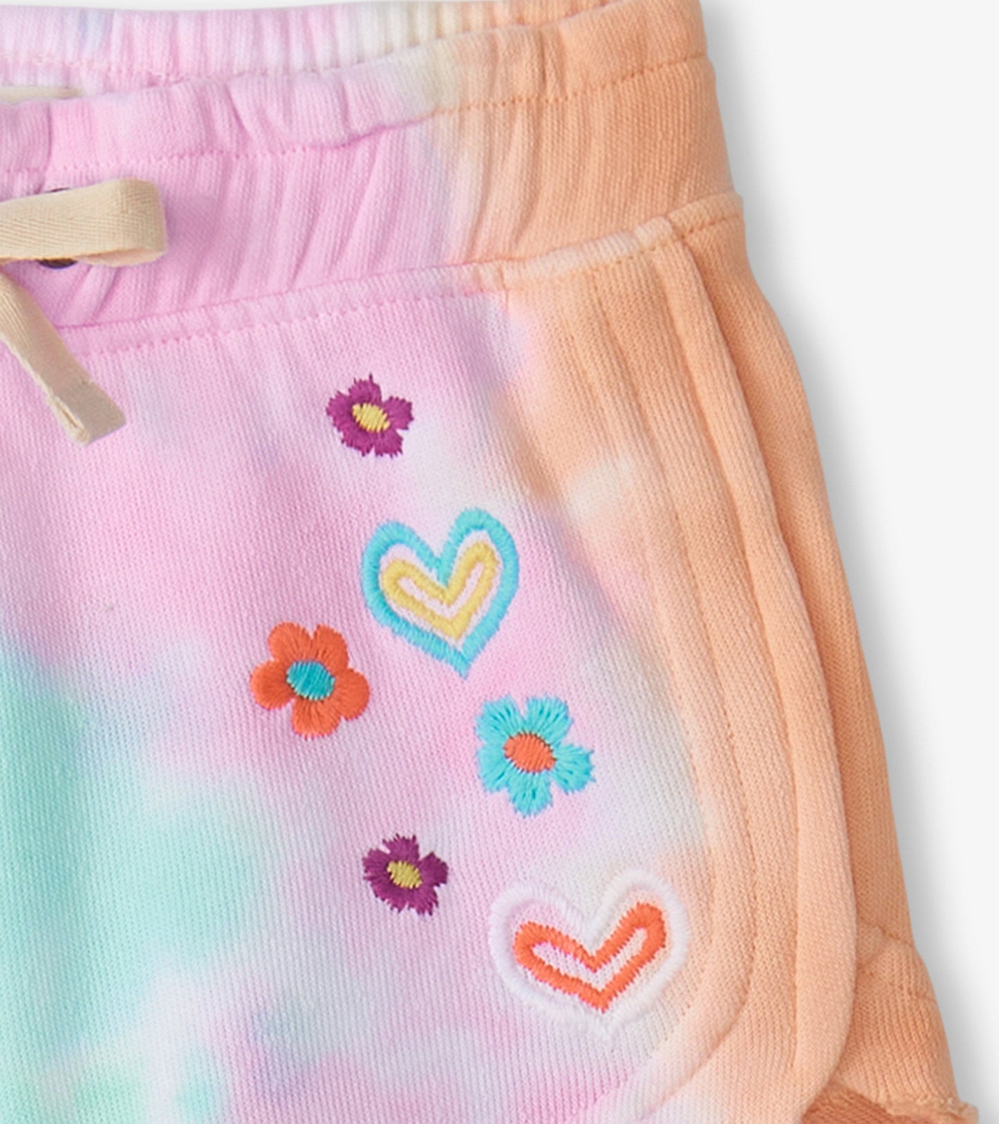 Pastel tie-dye pull-on shorts featuring colorful embroidered hearts and flowers, ideal for summer wear.
