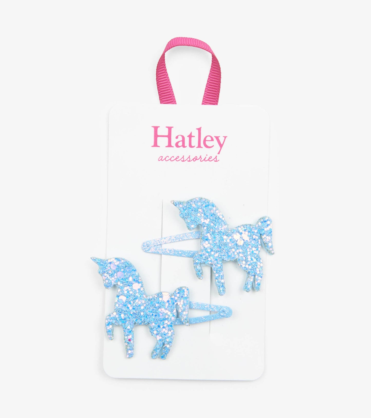 Two glittery blue unicorn snap clips on a white card with a pink ribbon.