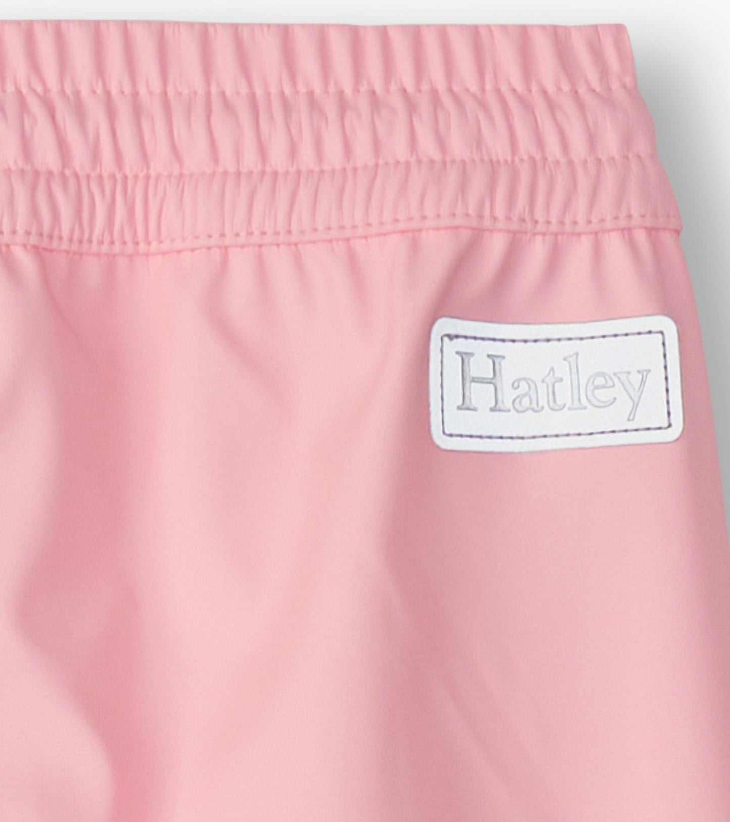Light pink kids' rain pants with an elastic waistband, designed for outdoor play in wet weather.