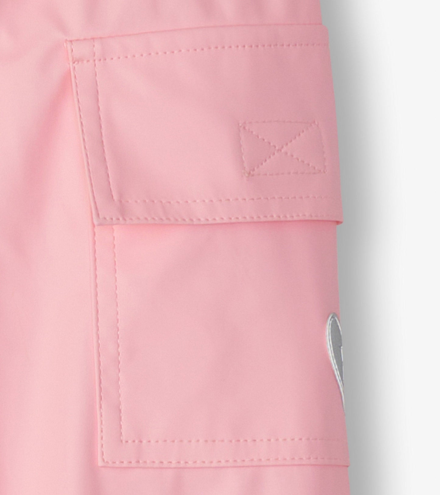 Light pink rain pants featuring a side pocket and a heart detail, designed for kids.