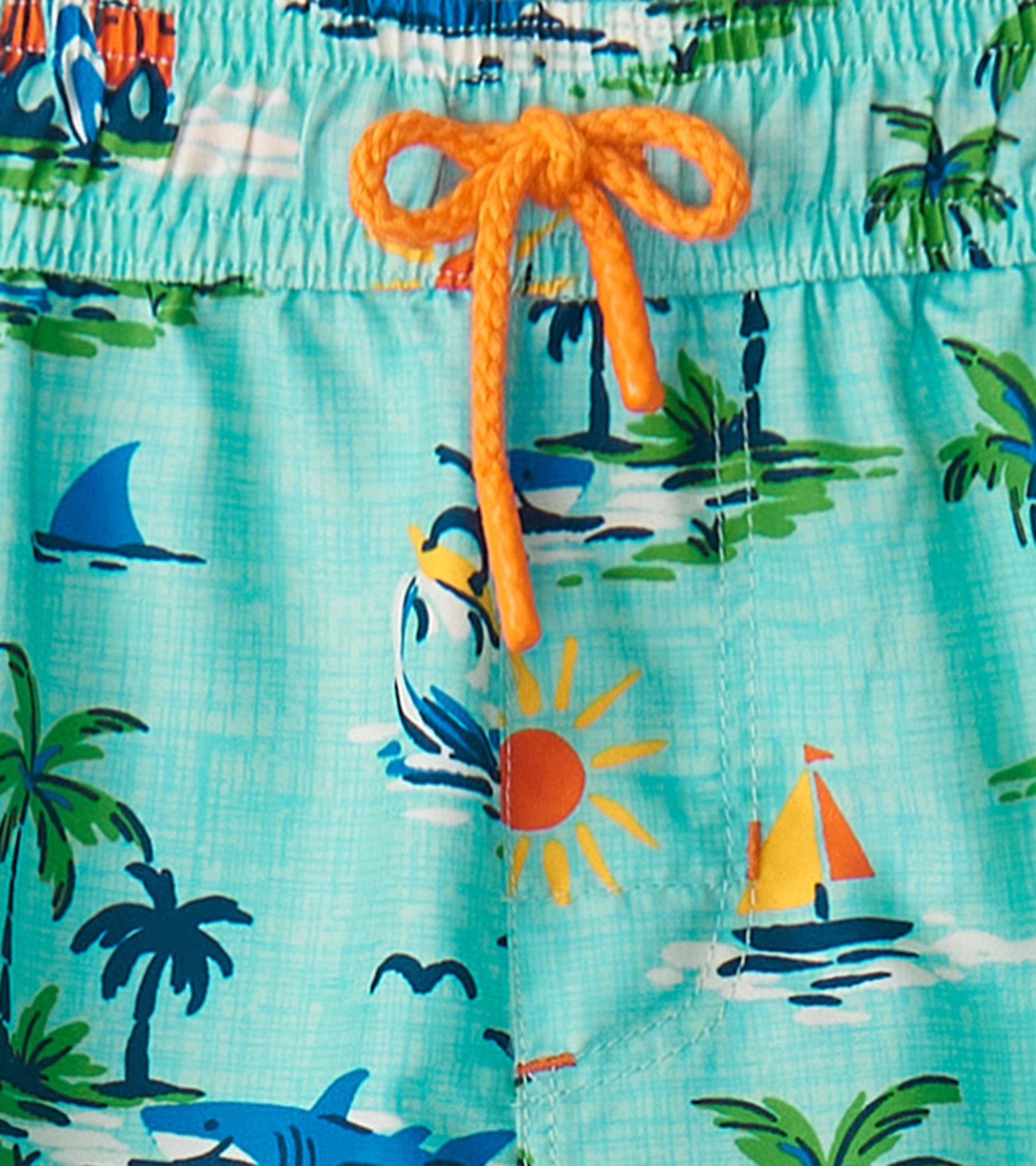 Turquoise board shorts featuring a tropical print with sharks, sailboats, and palm trees, finished with an orange drawstring.