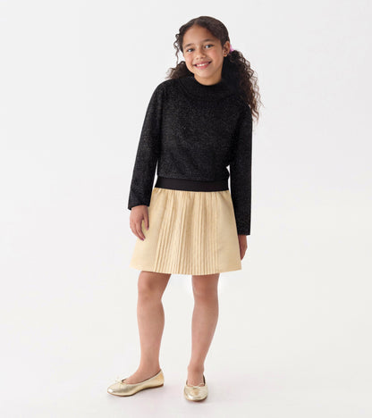 Black glitter turtleneck with long sleeves, paired with a pleated gold skirt.