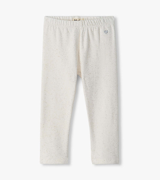 Infant cream leggings with an elastic waist, subtle metallic speckle print, and small hip emblem