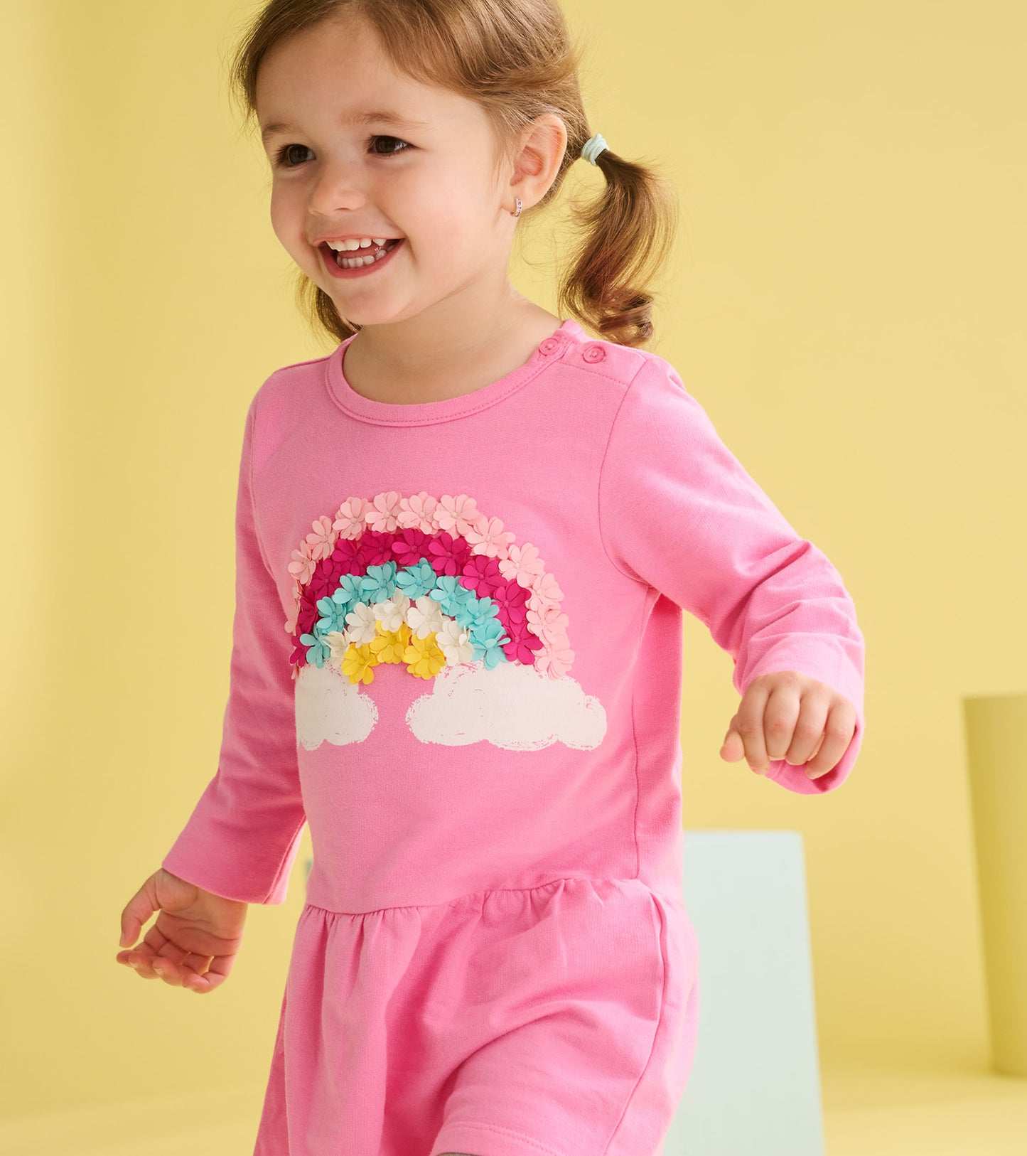 Pink long-sleeve toddler dress with rainbow and cloud graphic, front view