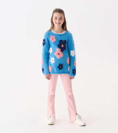 Blue furry sweater with colorful floral patterns, paired with light pink pants, worn by a smiling girl.