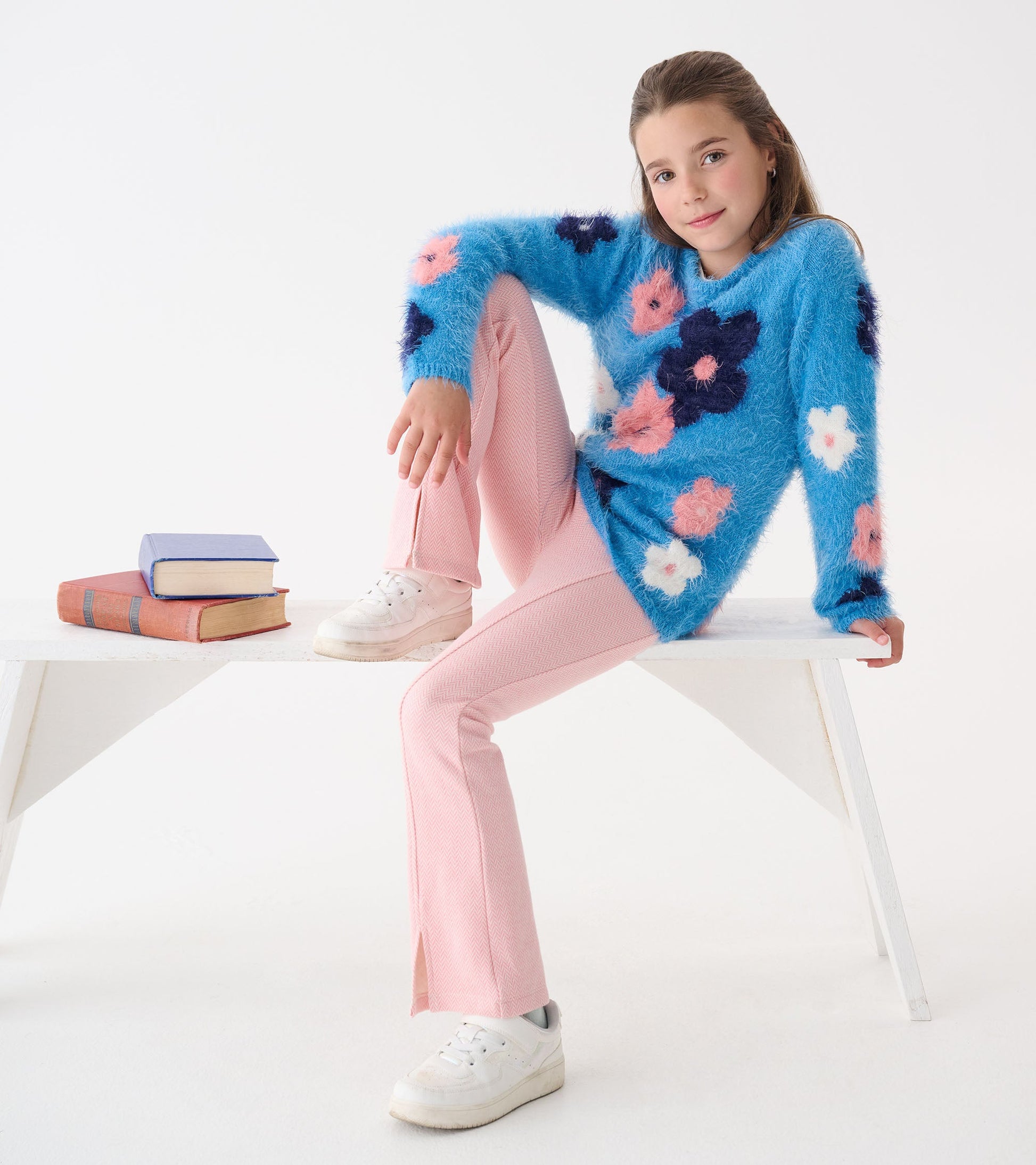 Furry blue sweater with colorful floral patterns, paired with pink pants and white sneakers, styled casually.