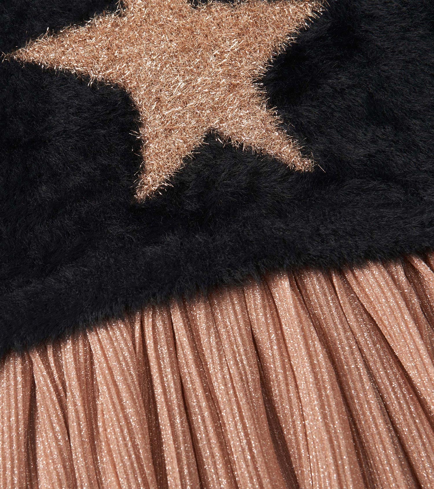 Black top with a gold star design and a pleated, shimmery rose gold skirt.