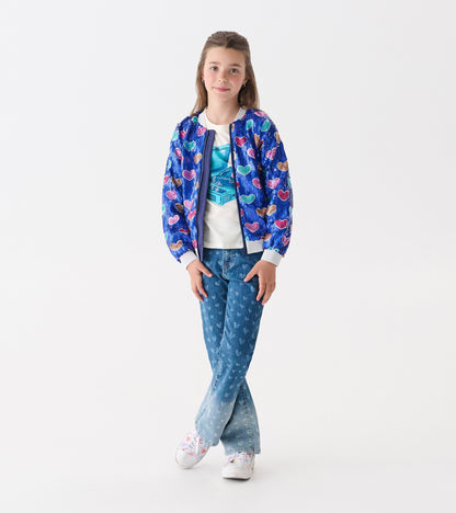 Blue bomber jacket with multicolored heart sequins, worn over a white shirt and paired with denim jeans.