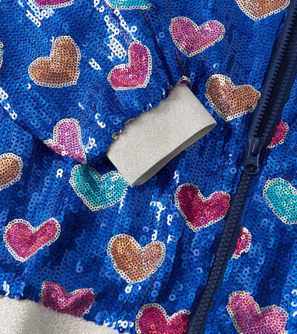 Blue sequin bomber jacket featuring colorful heart patterns and a gray ribbed cuff. Zipper closure visible.