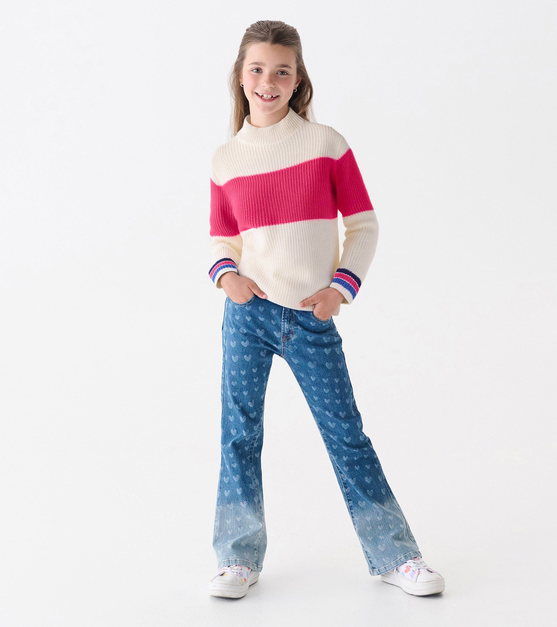 Girls' mockneck sweater featuring a cream base with a pink colorblock stripe and multicolored striped cuffs.