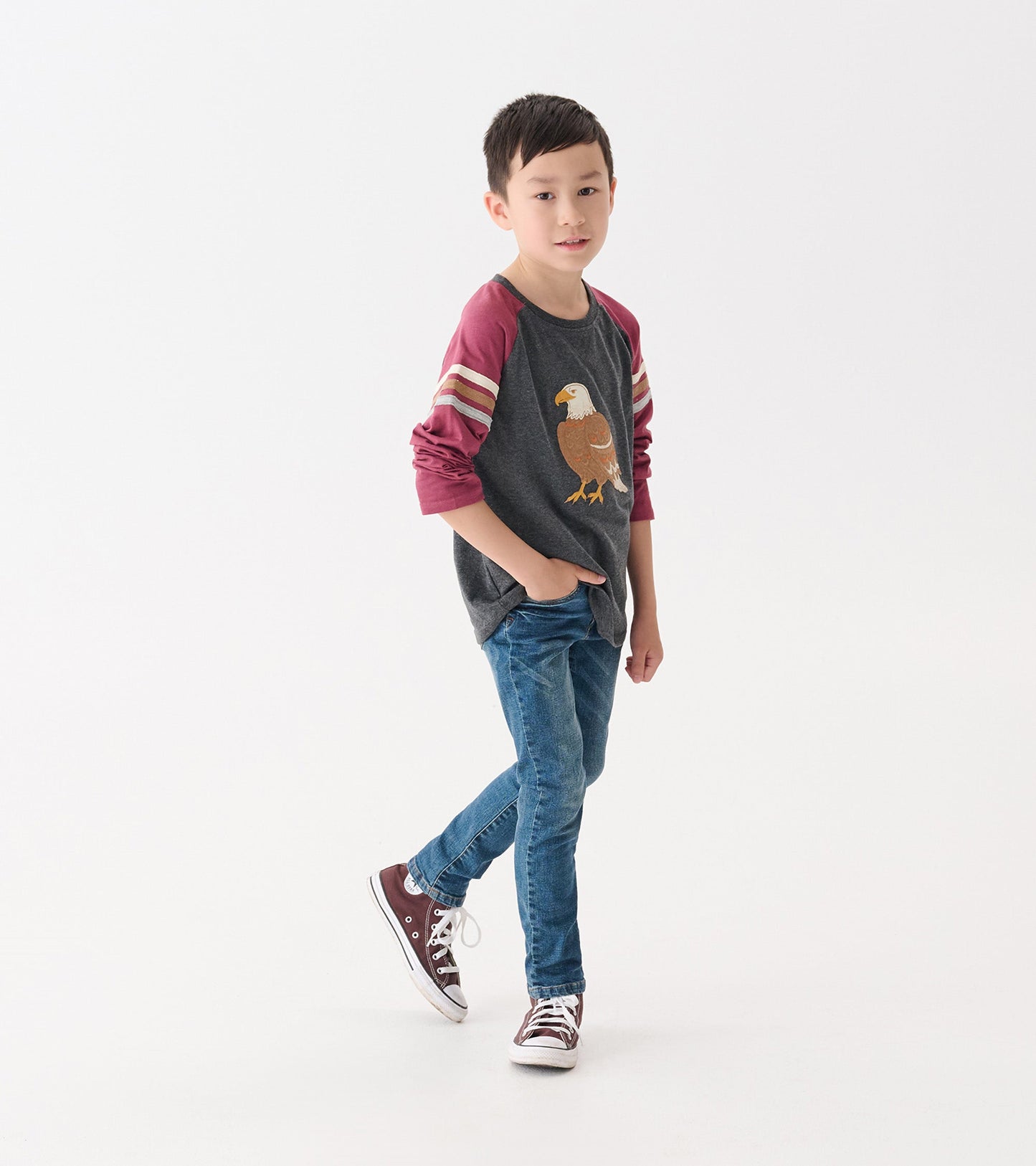Gray long sleeve raglan t-shirt with maroon sleeves and eagle graphic, worn by a boy with blue jeans and sneakers.